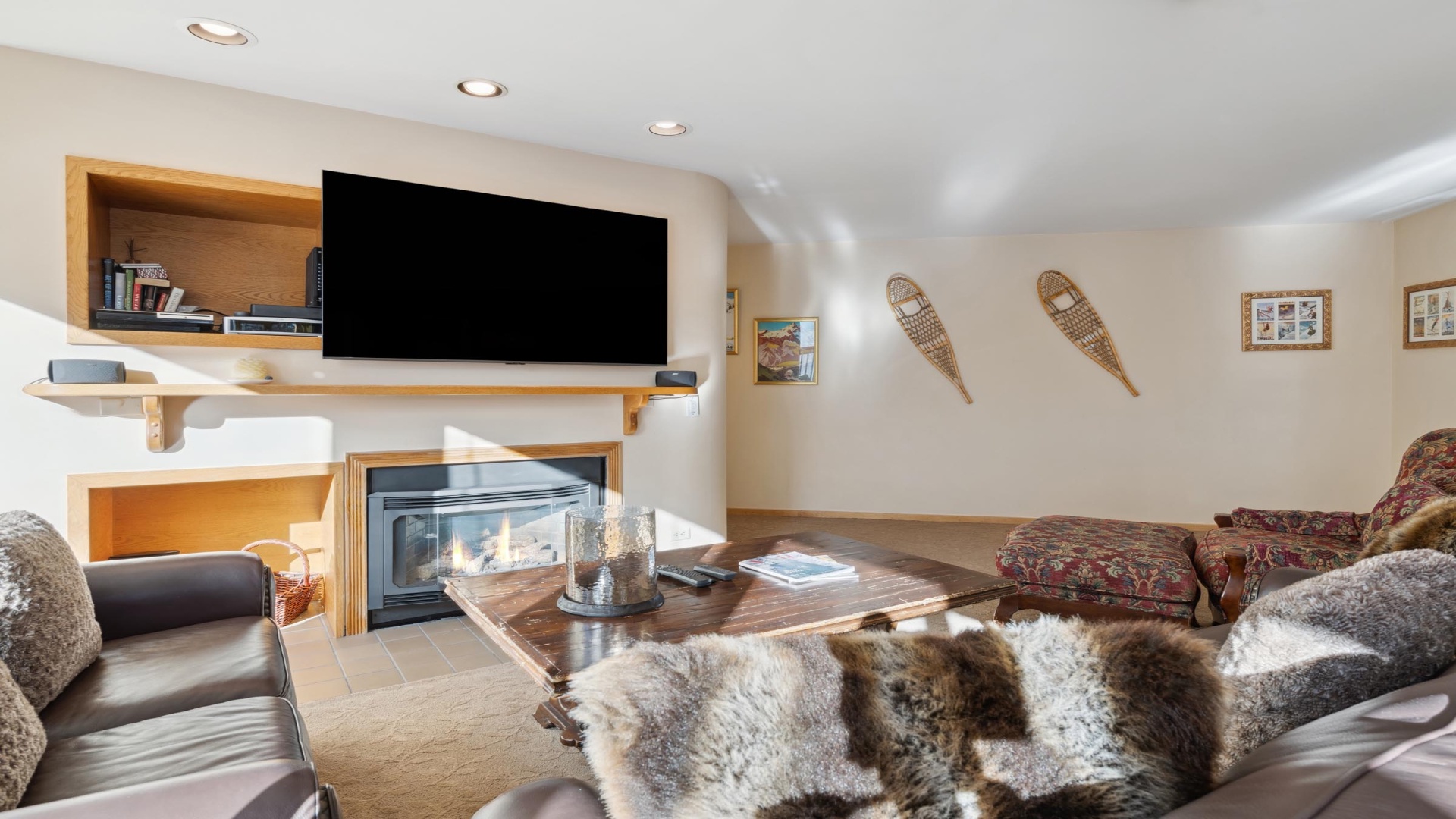 Sink into plush seating beside your own crackling fireplace, while rustic snowshoes and warm wood accents create a cozy mountain retreat for unwinding after alpine adventures.
