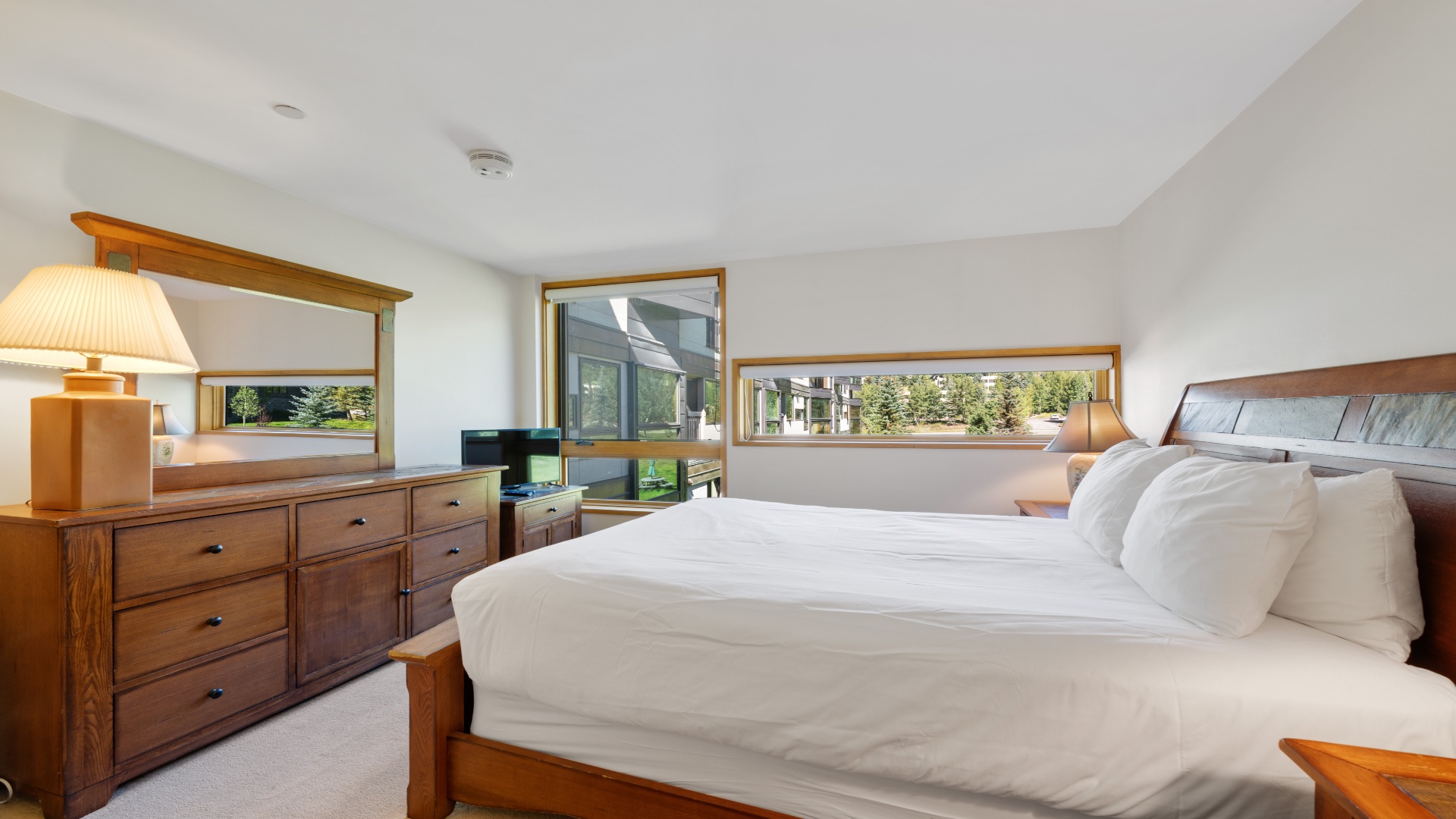 Sink into crisp linens and wake to peaceful neighborhood views from your private bedroom retreat, complete with warm wood furnishings and natural light.