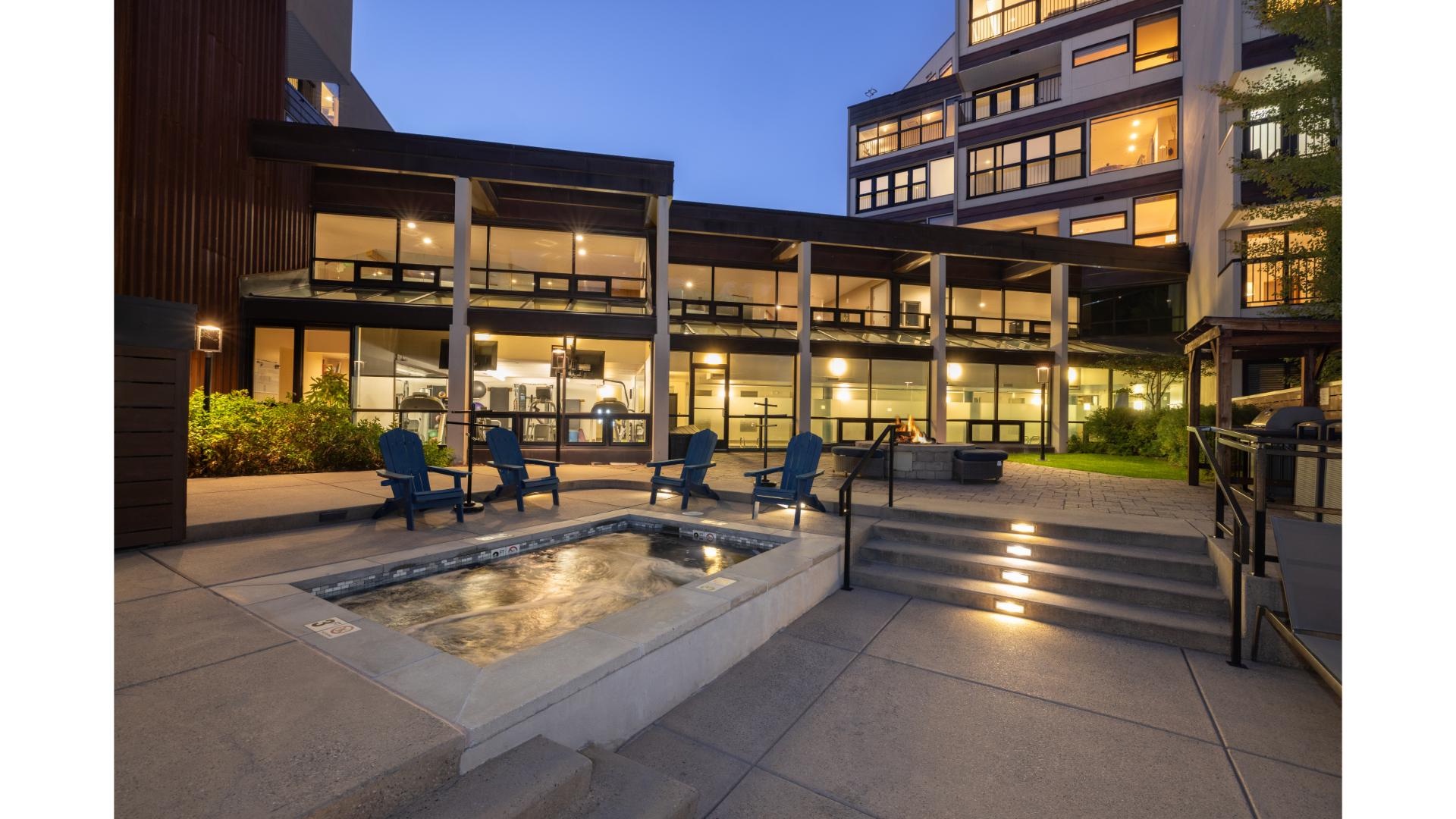 Modern property with a sleek courtyard featuring a hot tub, lounge seating, and beautifully lit communal spaces perfect for unwinding after a day of exploring.