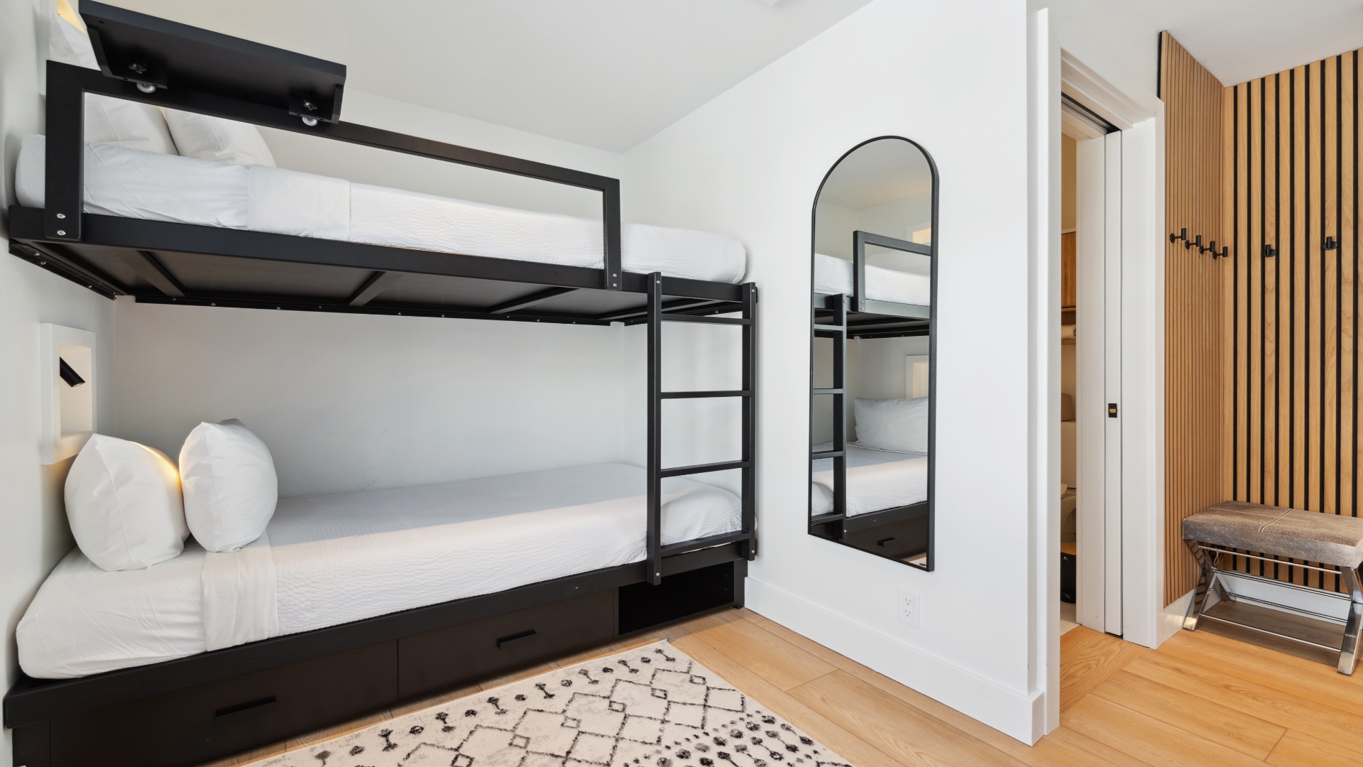Sleep soundly in this bright, modern bunk room with stylish black metal frames and cozy white linens. Your group will love the efficient layout and thoughtful design touches.