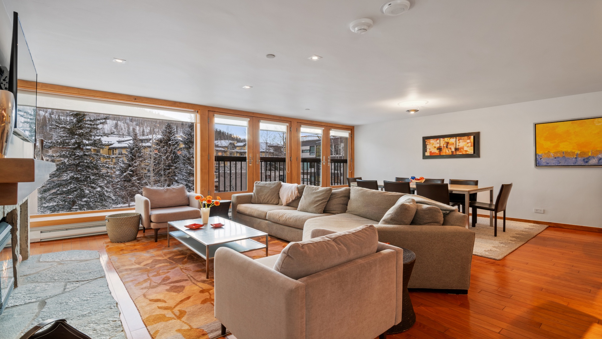 Sink into plush sofas and soak up panoramic winter mountain views through floor-to-ceiling windows. Your cozy retreat with warm wood tones and open space awaits.