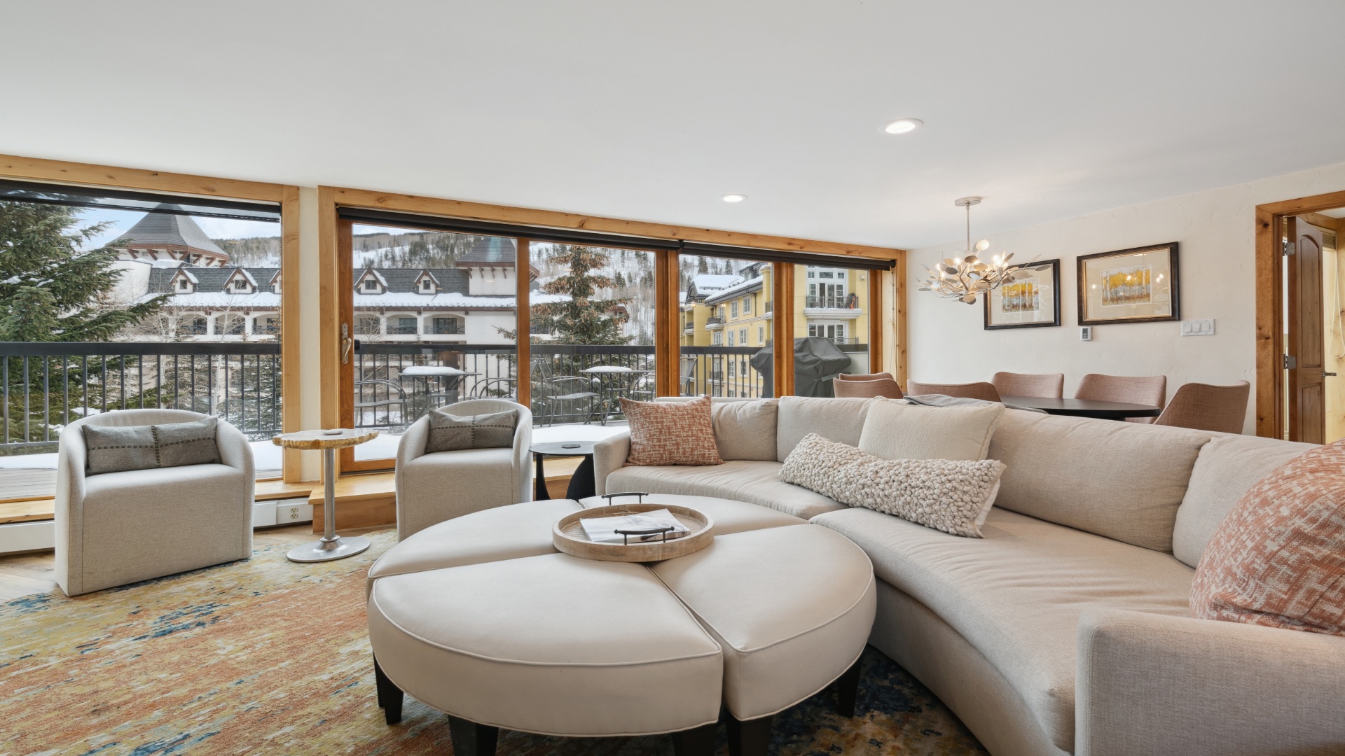 Sink into plush seating and soak up mountain village views through expansive windows. Your cozy living space blends modern comfort with warm wood accents, perfect for unwinding after a day on the slopes.