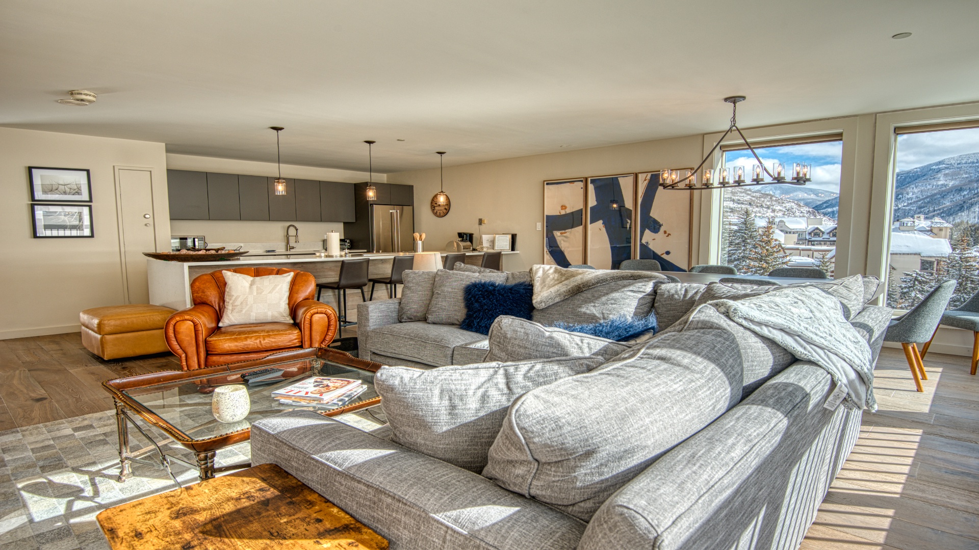 Unwind in your open-concept living space with cozy seating, modern kitchen access, and breathtaking mountain views framing your entire stay in natural light and alpine beauty.