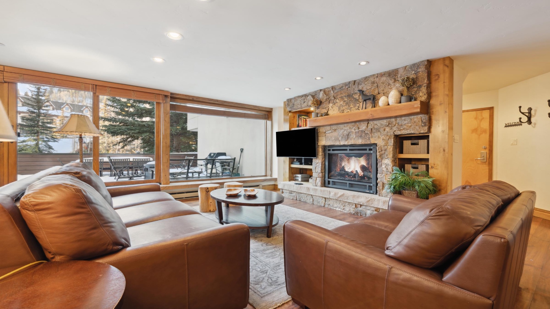 Relax in your spacious living room with plush leather sofas, a crackling fireplace, and mountain views through expansive windows—your perfect retreat after a day of adventure.