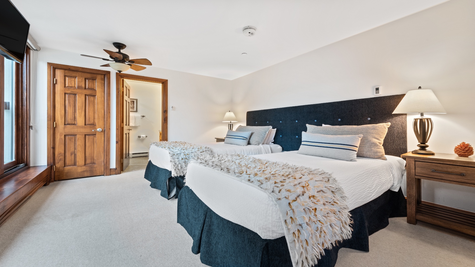 Sink into plush bedding and unwind in your private retreat. The ceiling fan keeps you cool while warm wood tones and soft lighting create a restful, inviting atmosphere.