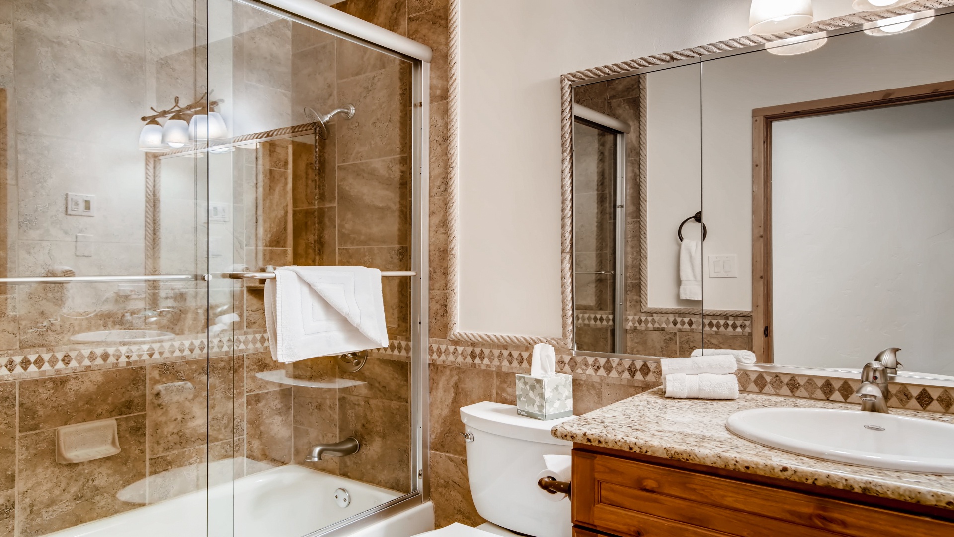 Step into your elegant bathroom with rich marble-like tile, a soaking tub-shower combo, granite vanity, and plush towels waiting for you.