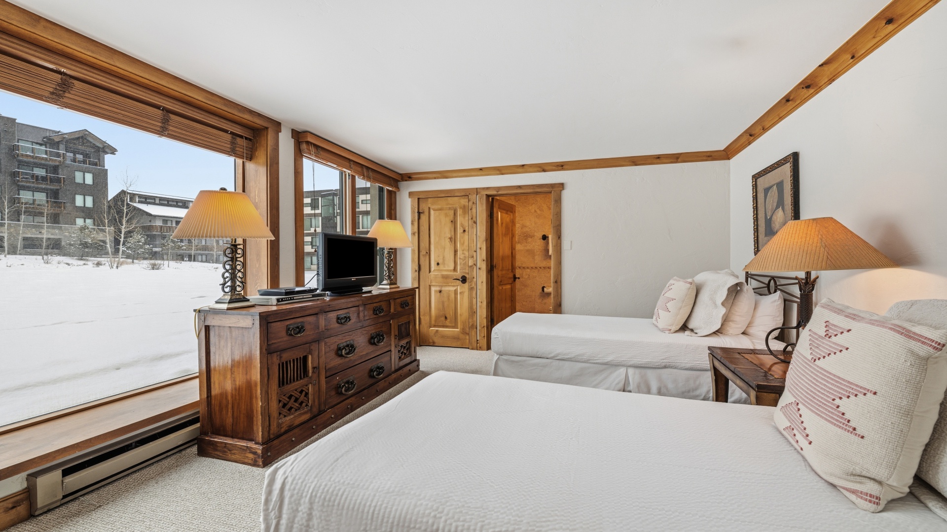Unwind in your cozy bedroom with rustic wood accents and two comfortable beds. Wake to peaceful snowy views and enjoy modern amenities like your flat-screen TV and warm ambient lighting.