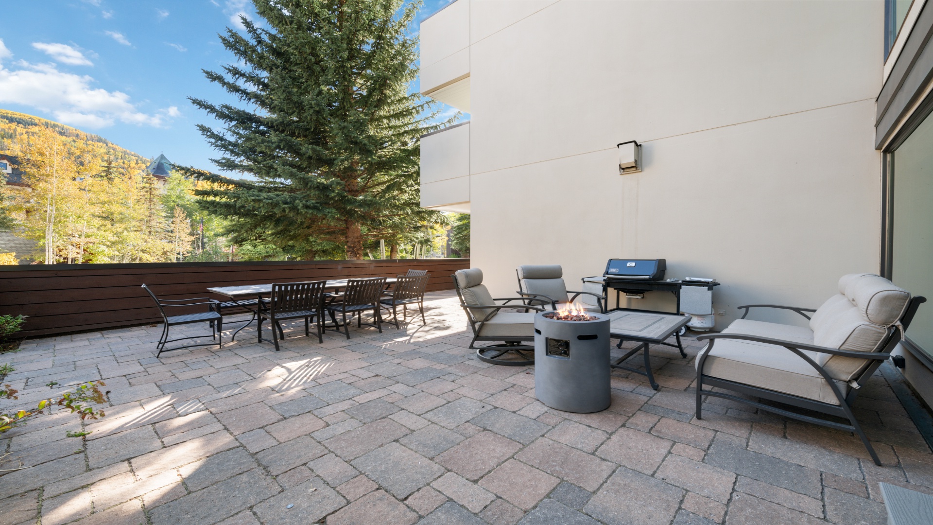 The spacious outdoor terrace and lounge area offers stunning views and a peaceful setting with mountain vistas and trees. A patio with ample dining seating and a modern gas grill provide the perfect outdoor gathering spot.