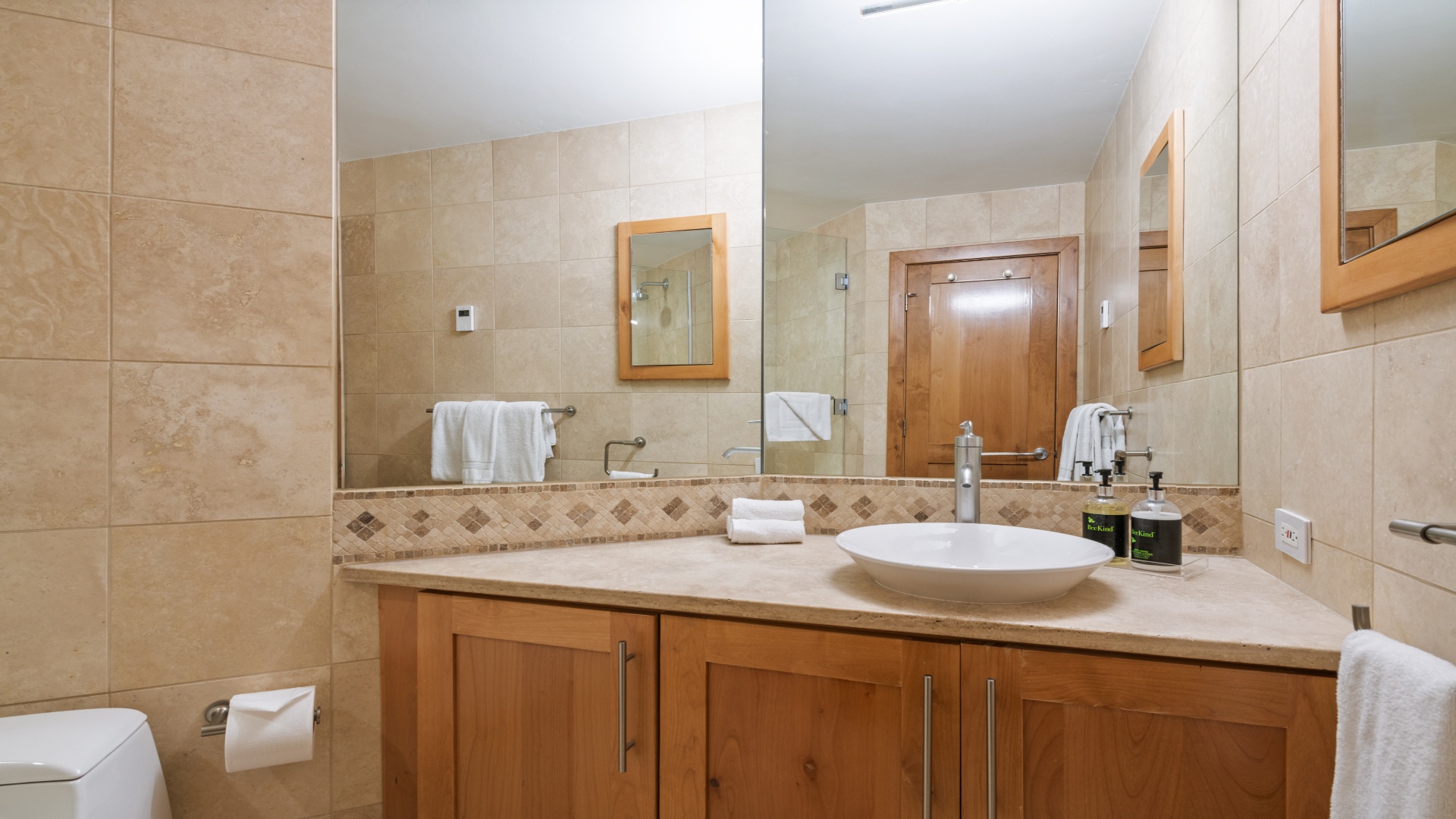 Step into your private spa-like retreat with warm stone tiling, sleek vanity, and plush towels ready for your refreshing morning routine.