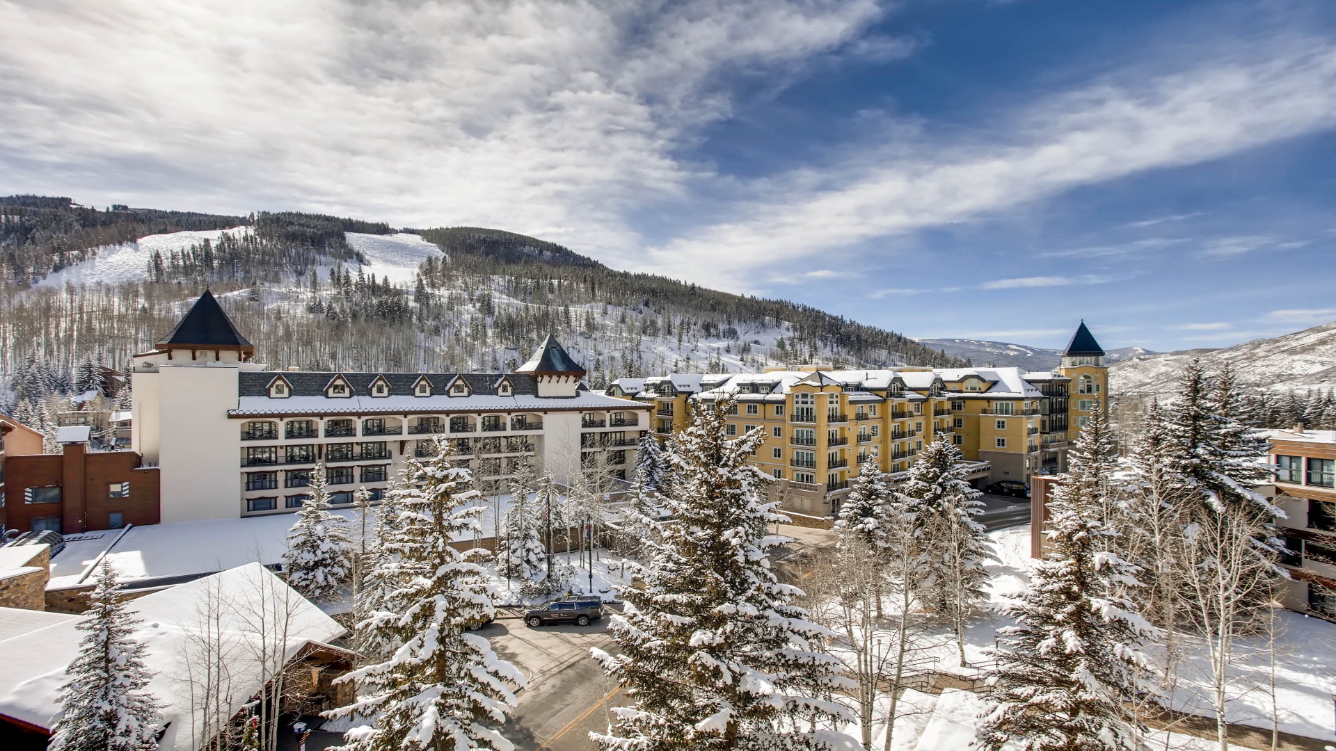 Snow-dusted alpine resort nestled beneath towering mountain peaks, offering a scenic mountain retreat surrounded by evergreen forests and winter beauty.