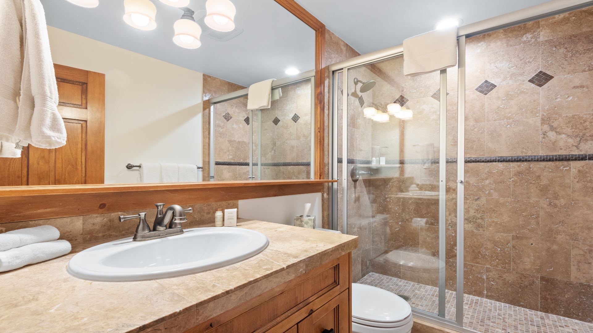 Step into your private bathroom, where warm earth tones and polished fixtures create a soothing retreat. The walk-in shower's elegant tile work and plush towels invite you to relax after a day of adventure.