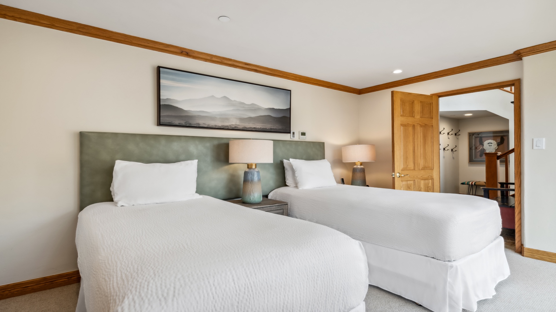 Settle into crisp white linens in your serene bedroom, where two plush beds and mountain artwork invite restful nights and peaceful mornings during your mountain escape.