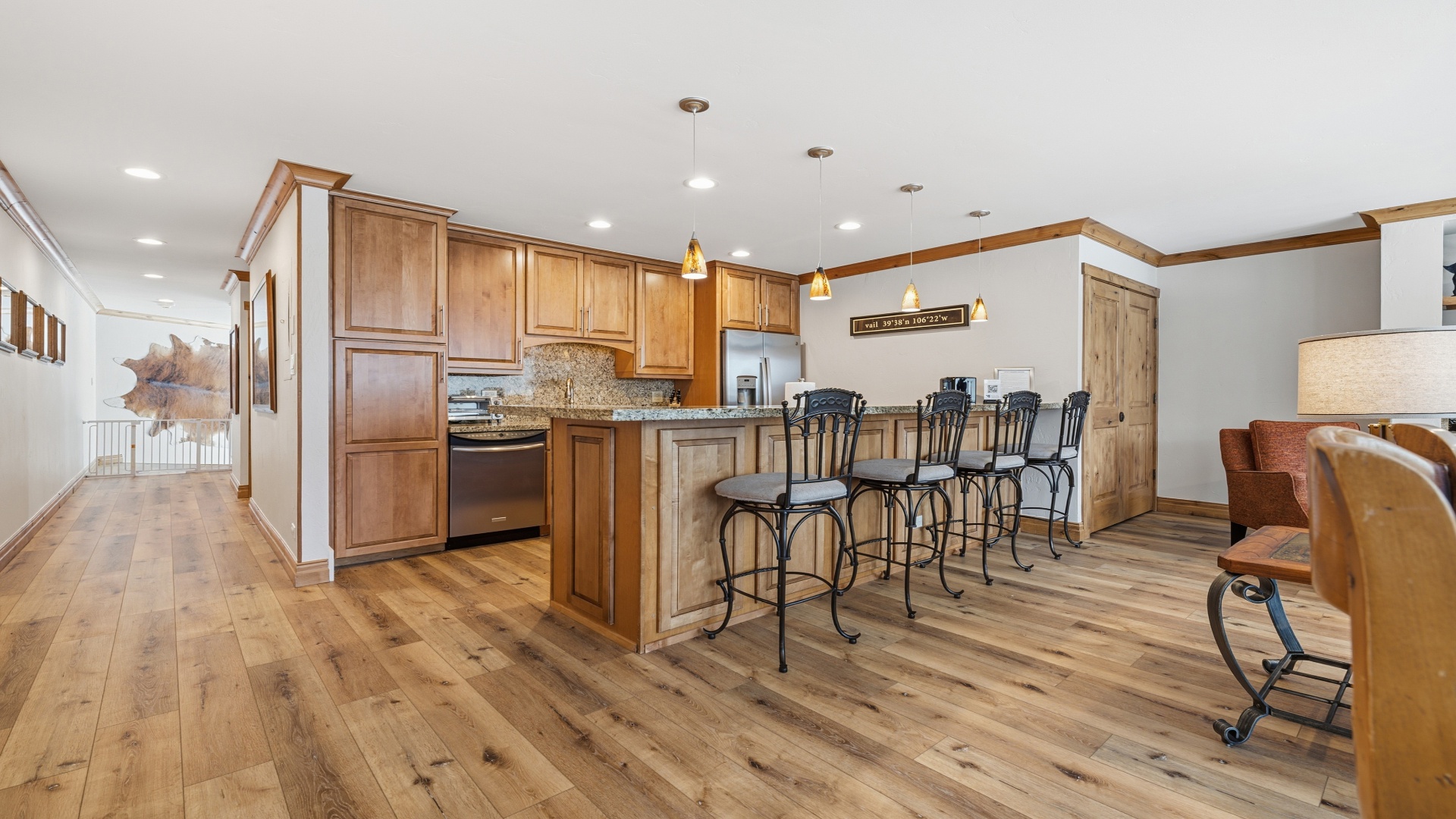 Step into your fully-equipped kitchen with rich wood cabinetry, stainless steel appliances, and an inviting island with seating for four—perfect for gathering over morning coffee or evening wine.