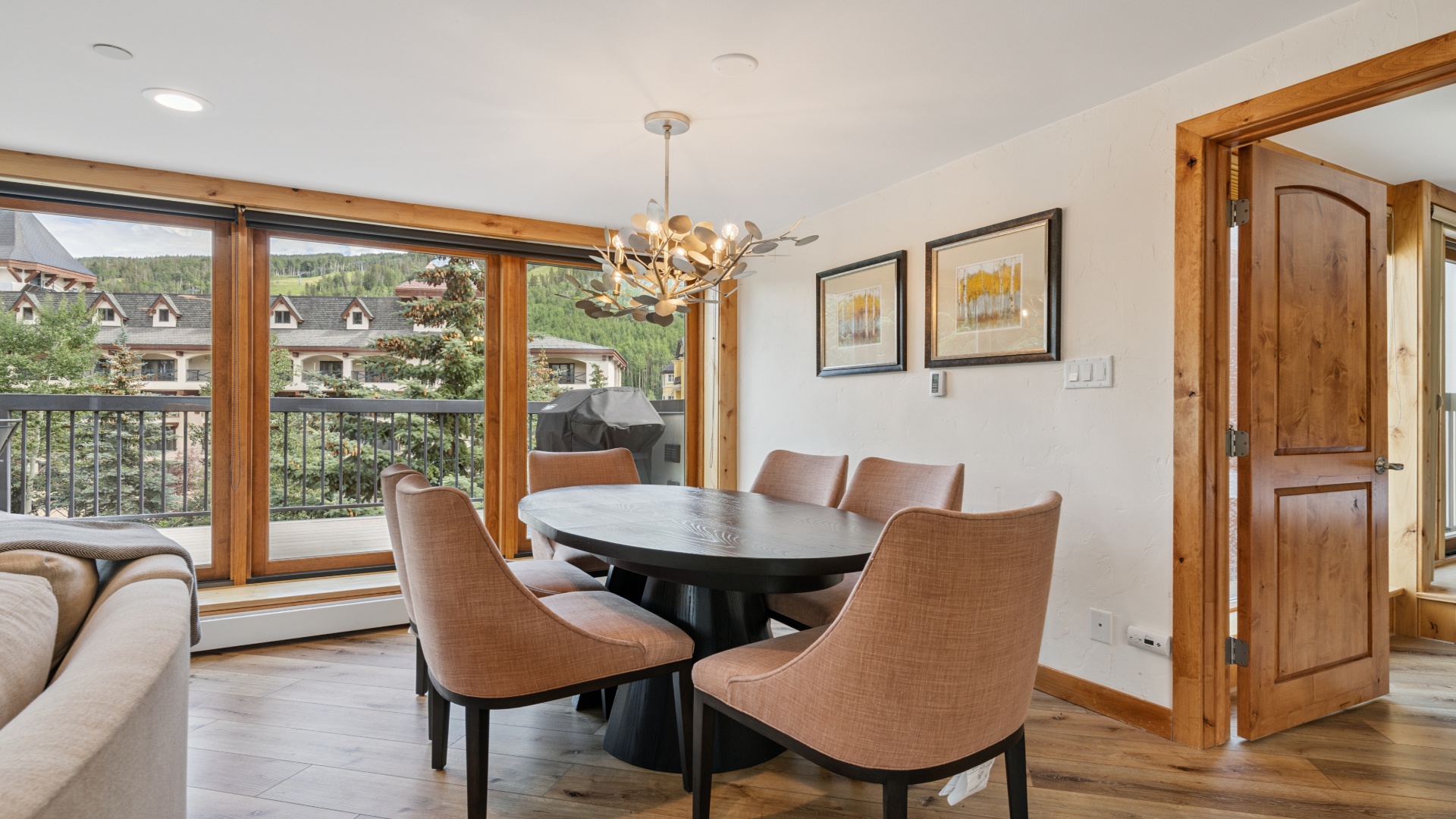 Gather around this stylish dining table where mountain views frame every meal. The modern chandelier and warm wood accents create an inviting space for your group to share stories and plan adventures.