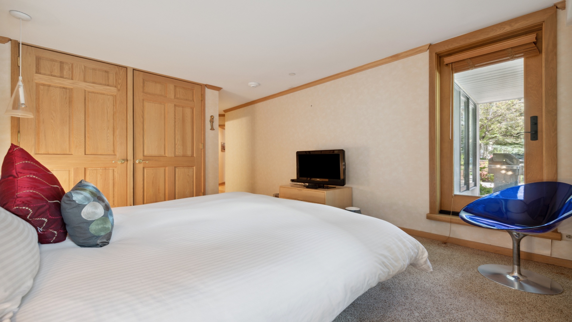 Your bedroom blends natural warmth with modern comfort—soft linens, warm wood tones, natural light, and a cozy seating nook for unwinding after exploring.