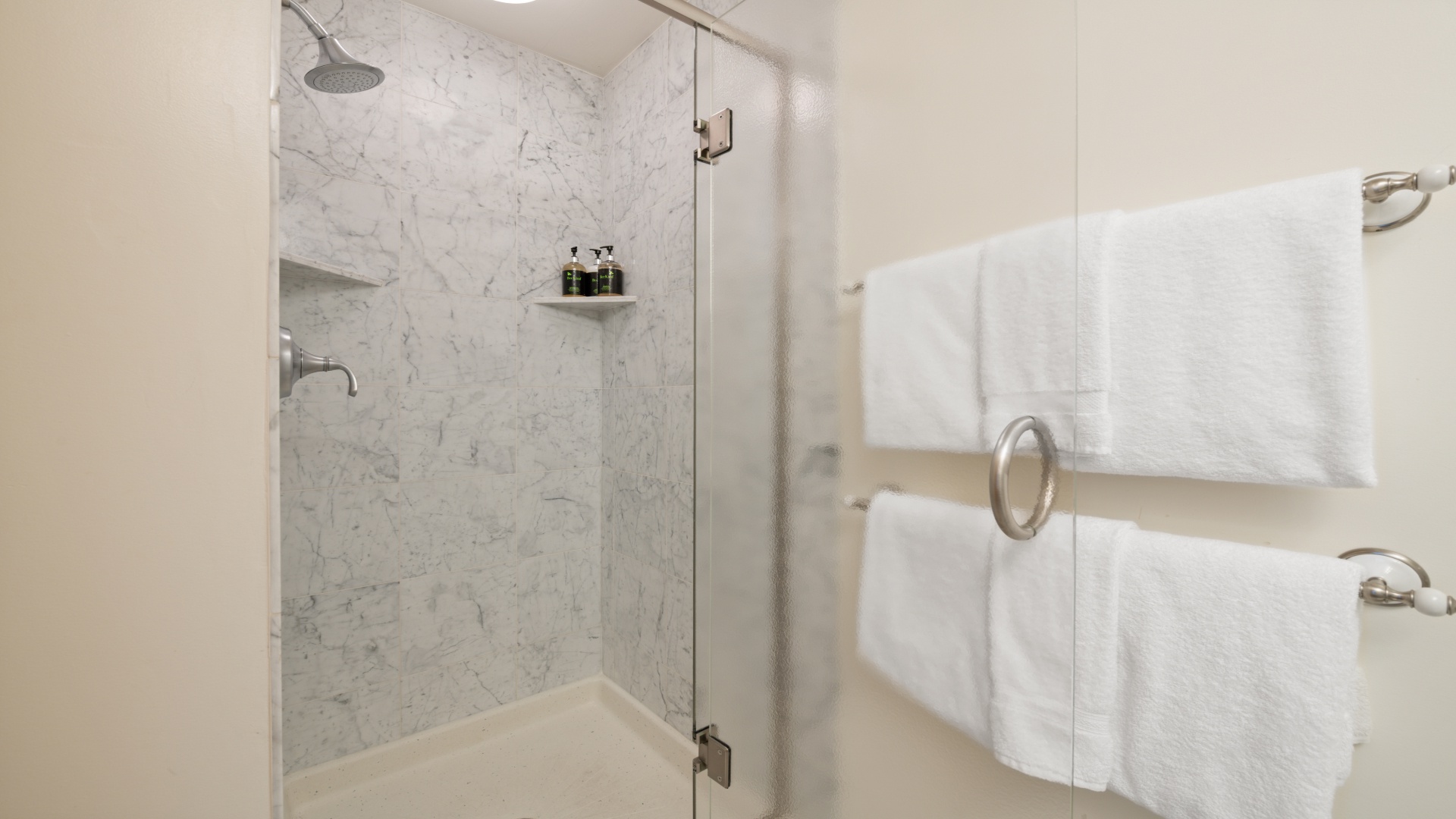 Step into your sleek marble-tiled shower where a rainfall showerhead awaits. Plush towels and thoughtful amenities ensure your comfort.