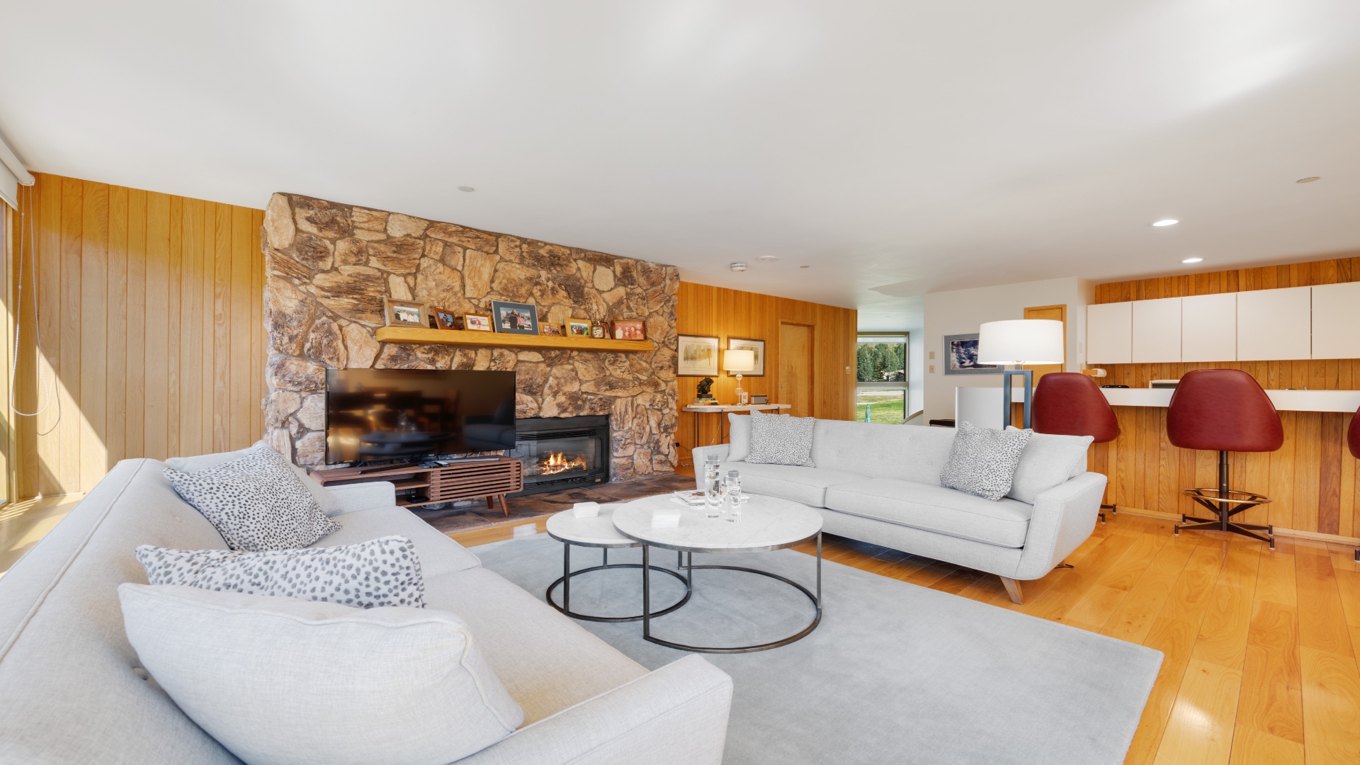 Sink into plush sofas by the crackling fireplace, surrounded by warm wood tones and natural stone. This open living area flows seamlessly from cozy relaxation to dining and entertaining.