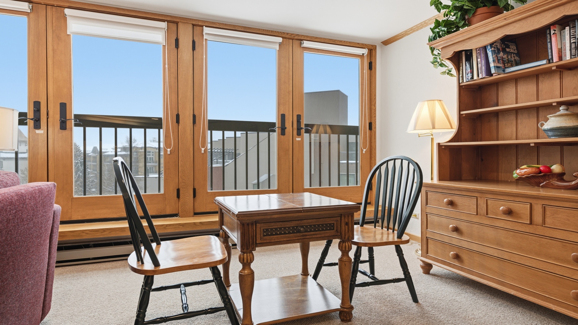 Settle into your cozy reading nook with warm wooden accents, comfortable seating, and plenty of natural light streaming through charming French doors opening to a private balcony.