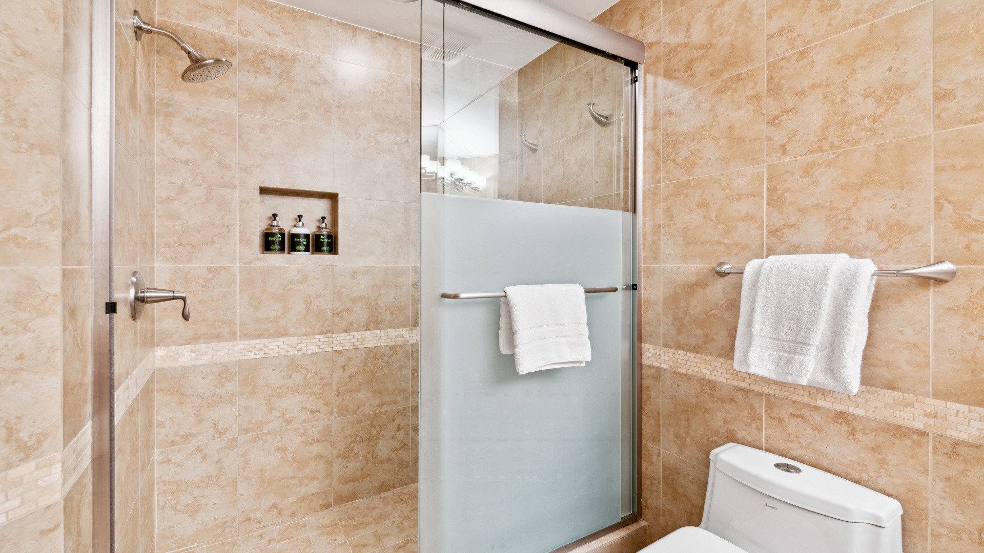 Step into your private spa-like retreat with a rainfall shower, modern glass enclosure, and plush towels waiting for you. Warm neutral tones create a soothing ambiance.