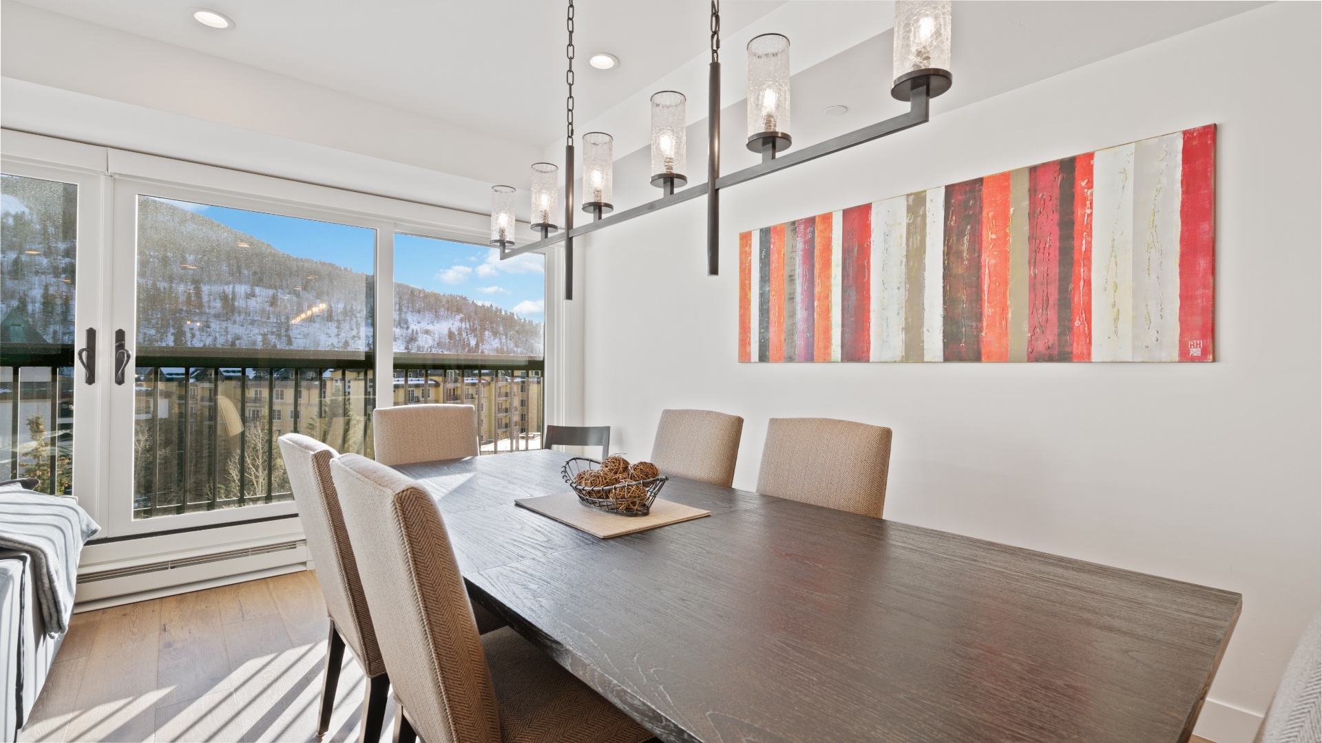 Gather for meals at this stylish dining table with stunning mountain views through floor-to-ceiling windows, creating the perfect backdrop for your vacation memories.