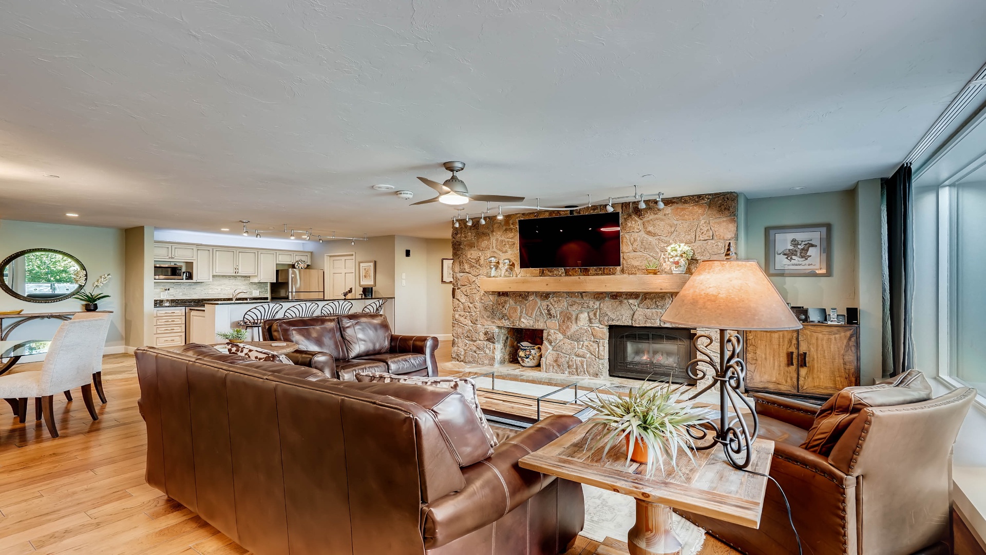 Unwind in this beautifully appointed open-concept living space, where rich leather seating, a grand stone fireplace, and gleaming hardwood floors create an inviting retreat for your mountain getaway.