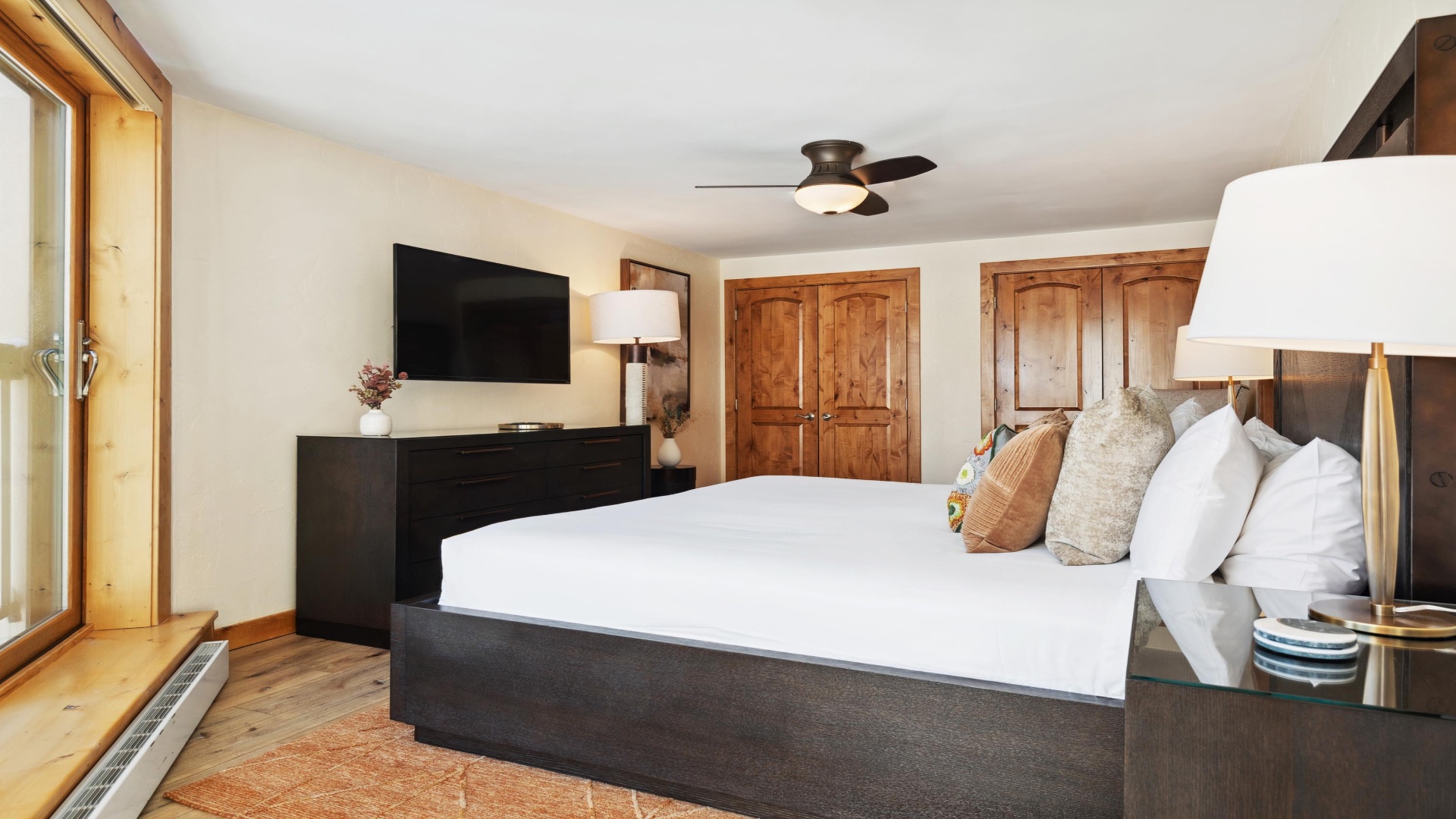 Sink into plush bedding and enjoy your favorite shows on the wall-mounted TV. Natural light and warm wood accents create a cozy mountain retreat feel.