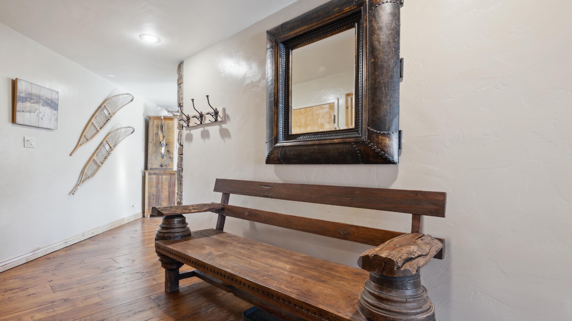 Step into your welcoming entryway, where rustic wood accents and vintage snowshoes create a cozy mountain retreat feel. This charming mudroom offers plenty of hooks for your gear after a day of adventure.