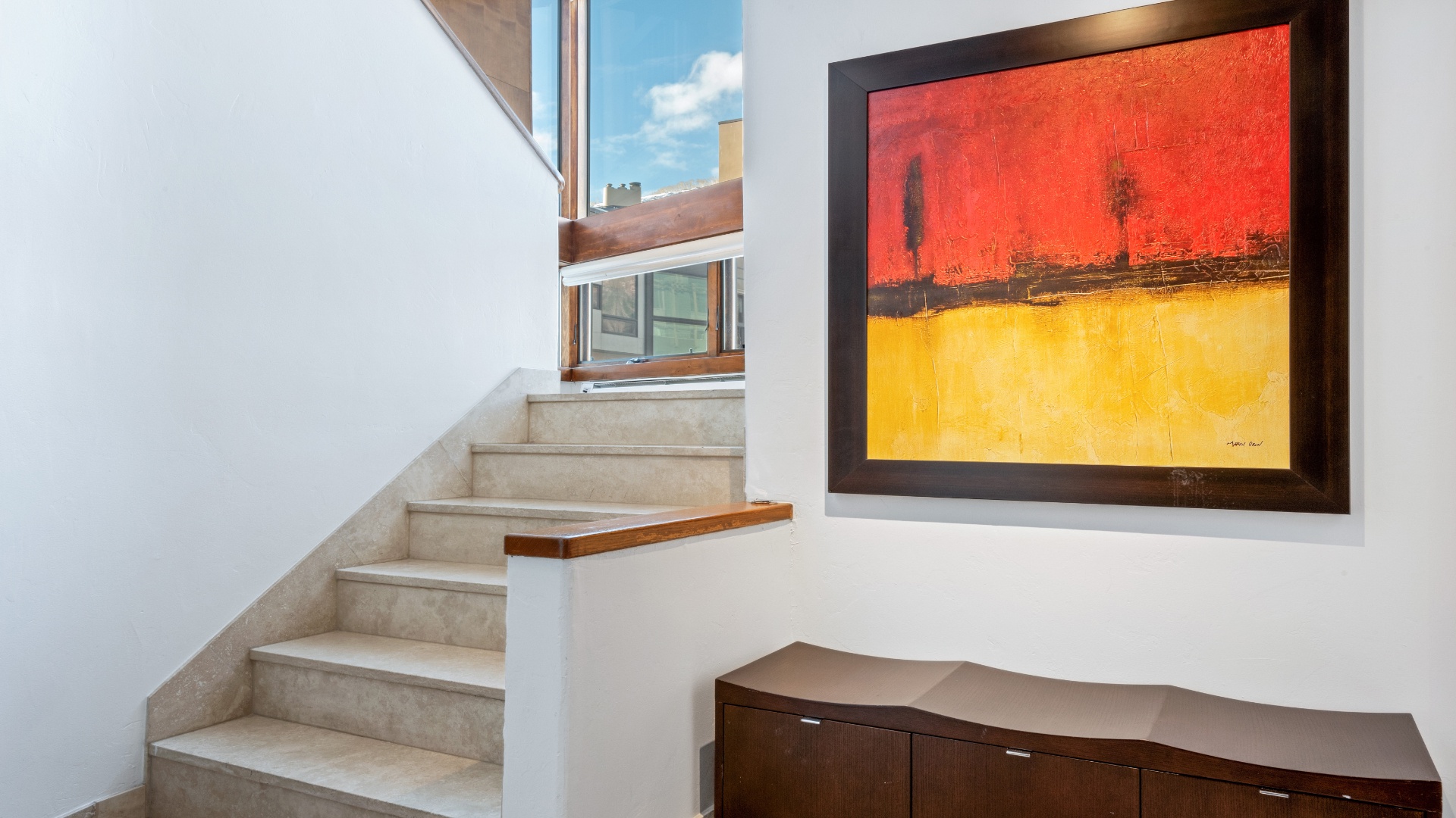 Bright stairwell with bold artwork adds character and warmth to your private space, connecting living areas under natural daylight streaming through expansive windows.