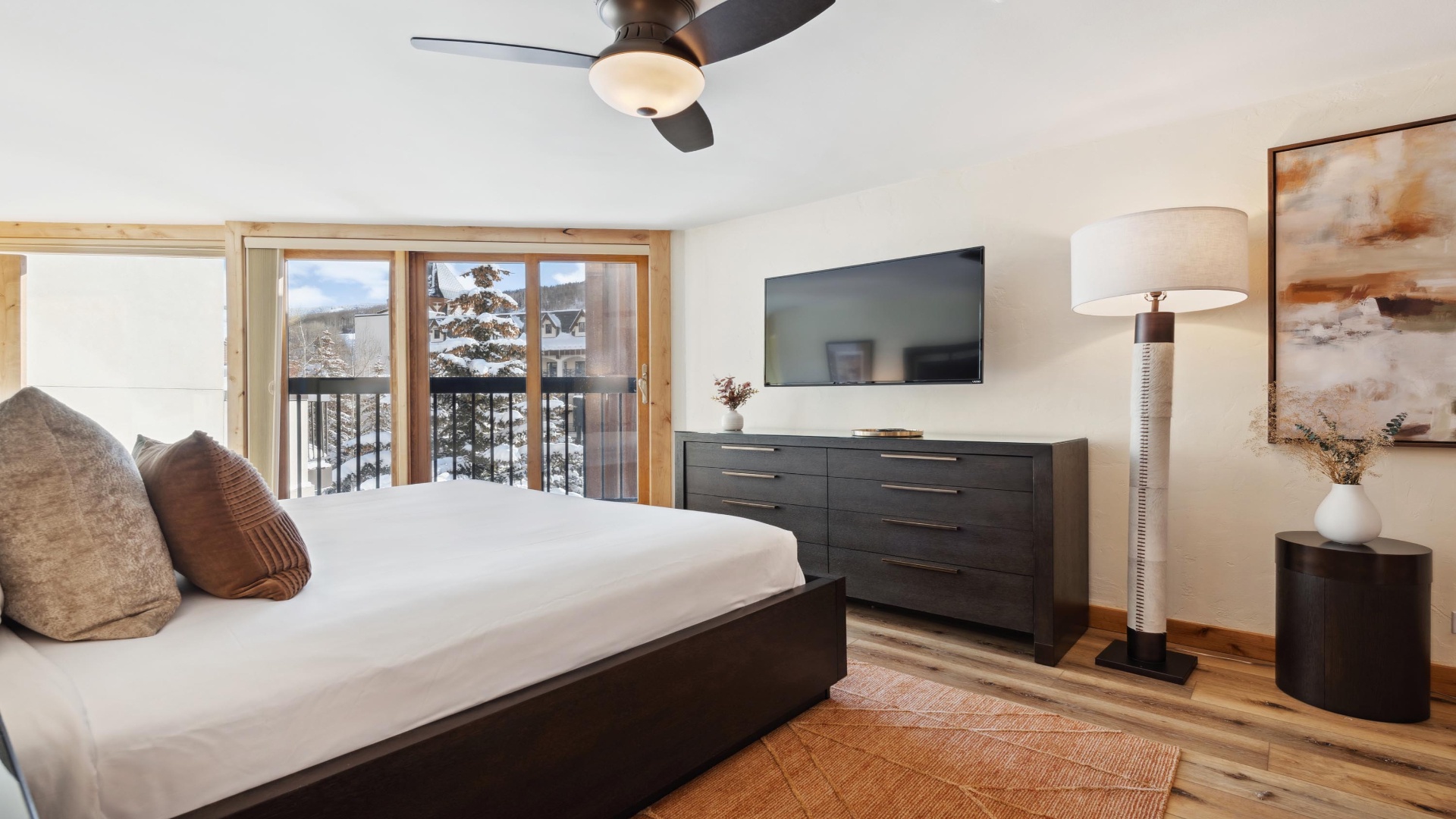 Step into your serene mountain retreat with a plush bed, modern entertainment, and stunning winter views from your private balcony—your perfect alpine escape awaits.