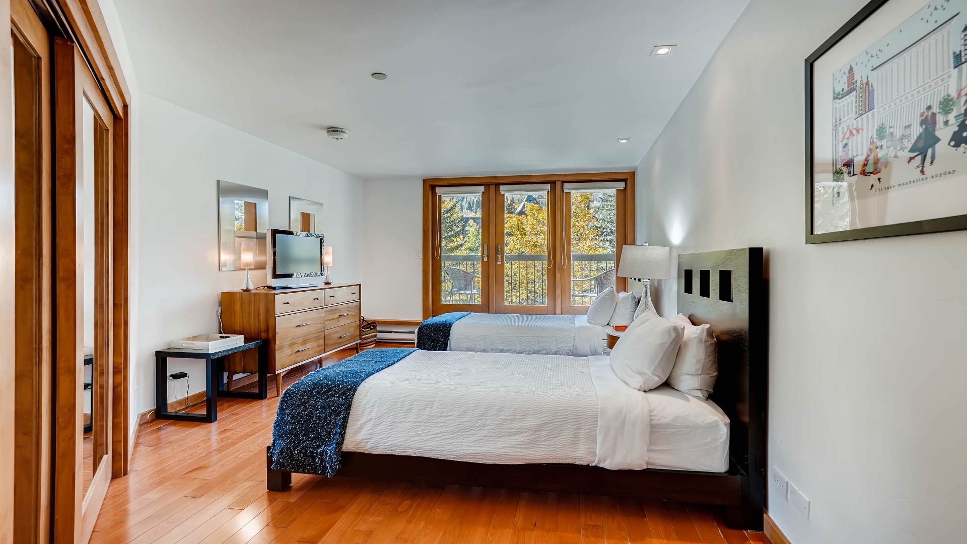 Wake up to natural light streaming through the tall windows in this bright, thoughtfully designed bedroom. Two plush beds await your restful stay, while warm wood accents create a welcoming retreat.