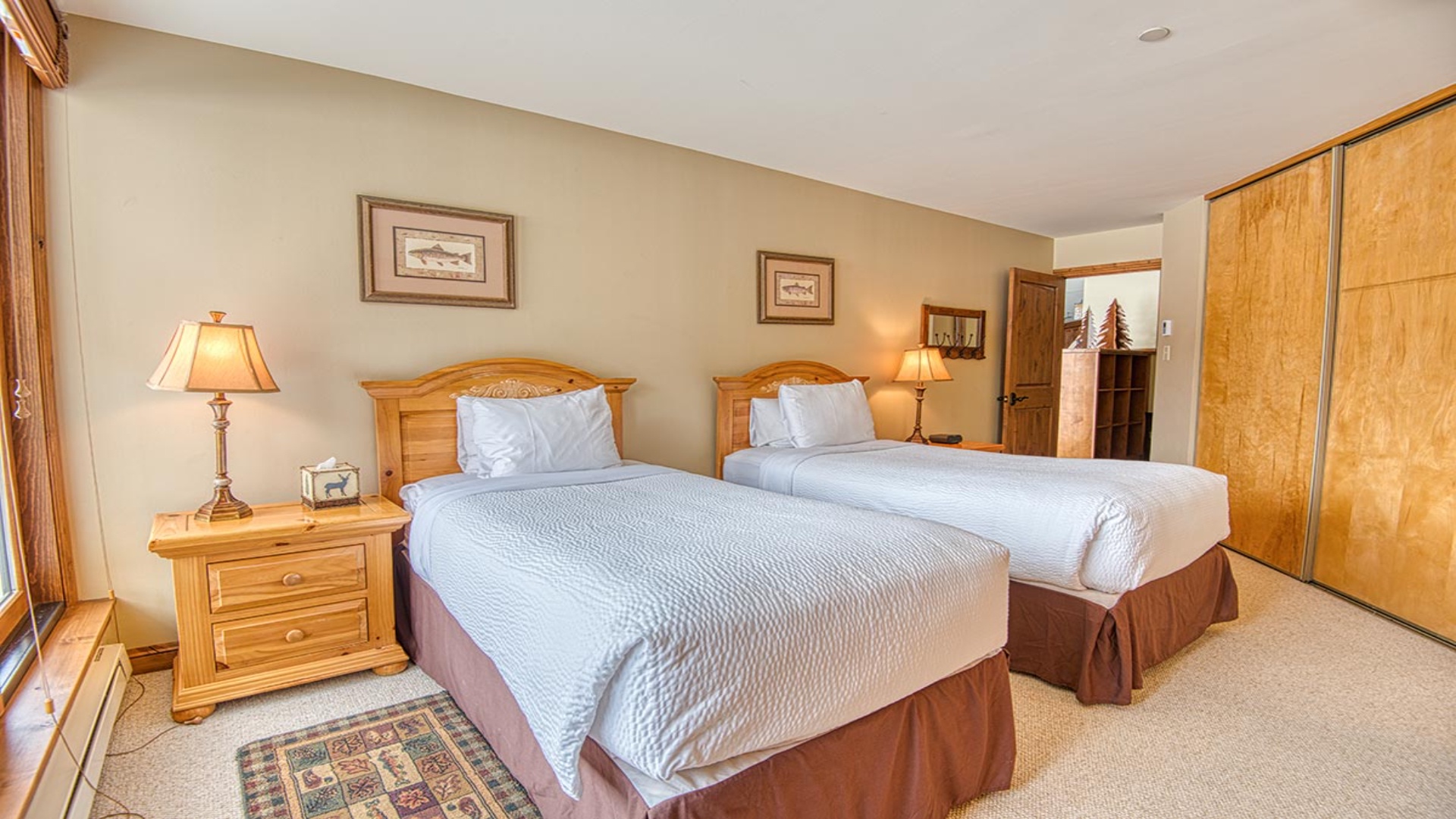 Two plush beds with crisp linens invite restful nights in your cozy mountain retreat, complete with warm wood furnishings and soft lighting for ultimate comfort.