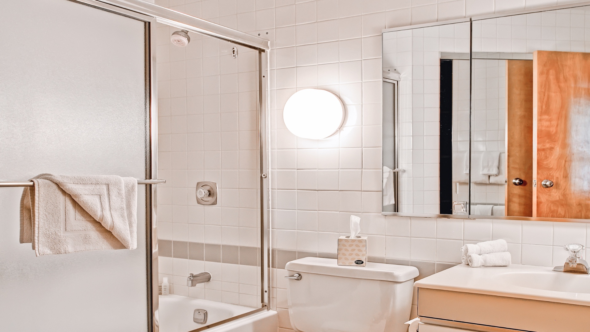 You'll love starting your day in this pristine, modern bathroom with a glass-enclosed shower, warm wood cabinetry, and plush fresh towels waiting for you.