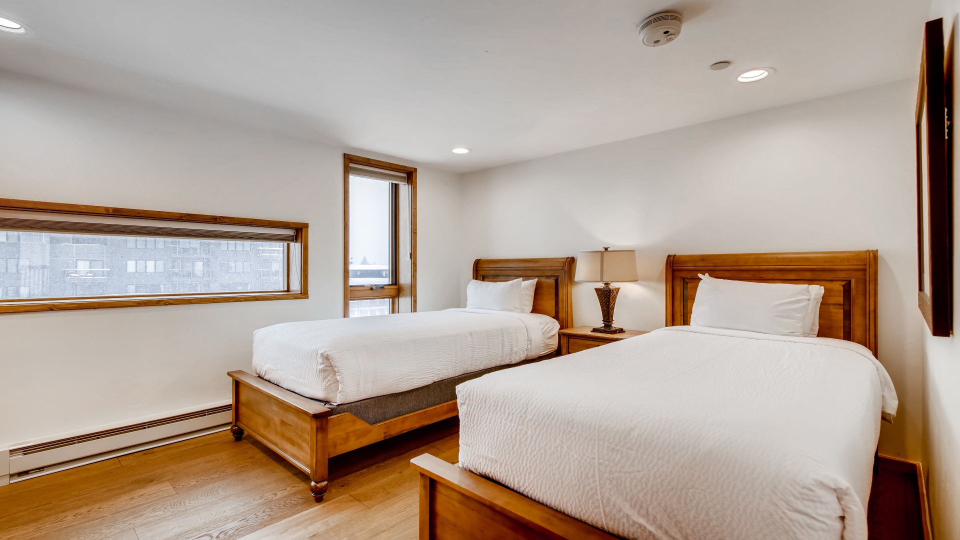 Two elegant twin beds with crisp linens await your restful nights, bathed in natural light from large windows overlooking the surrounding area.