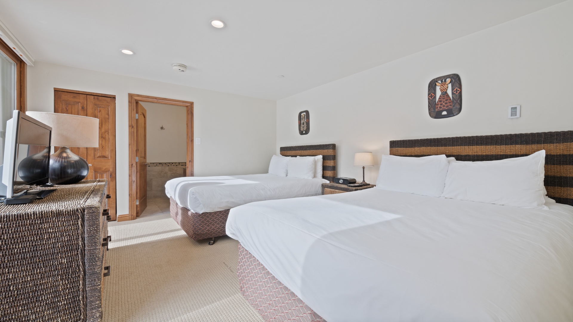 Sink into crisp white linens after a day of adventure. This tranquil room offers two comfortable beds, warm wood accents, and your own private en-suite bathroom just steps away.