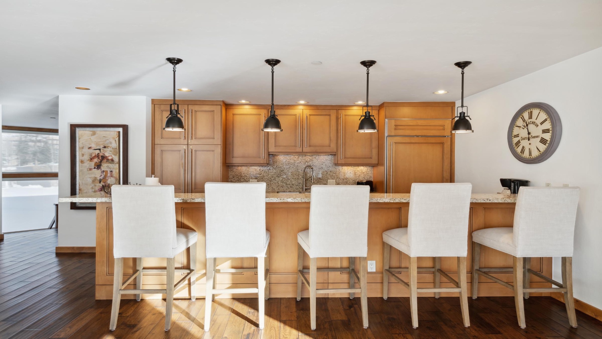 Pull up a seat at your gourmet kitchen island, where pendant lights illuminate granite countertops and warm wood cabinetry. Perfect for morning coffee or gathering with loved ones.