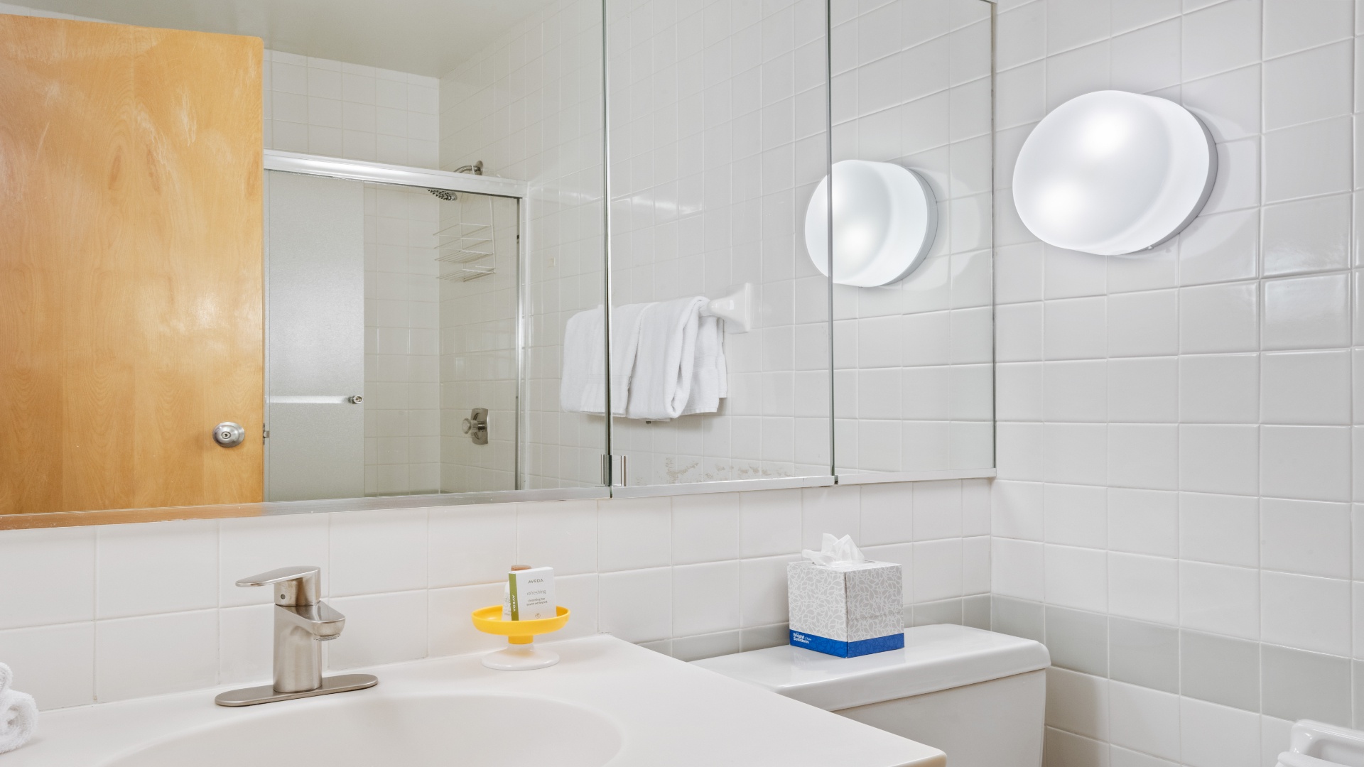 Step into your bright, modern bathroom where crisp white tiles and double sinks create a spa-like retreat. Enjoy fresh towels and thoughtful touches like magnifying mirrors as you prepare for your day or unwind after exploring.