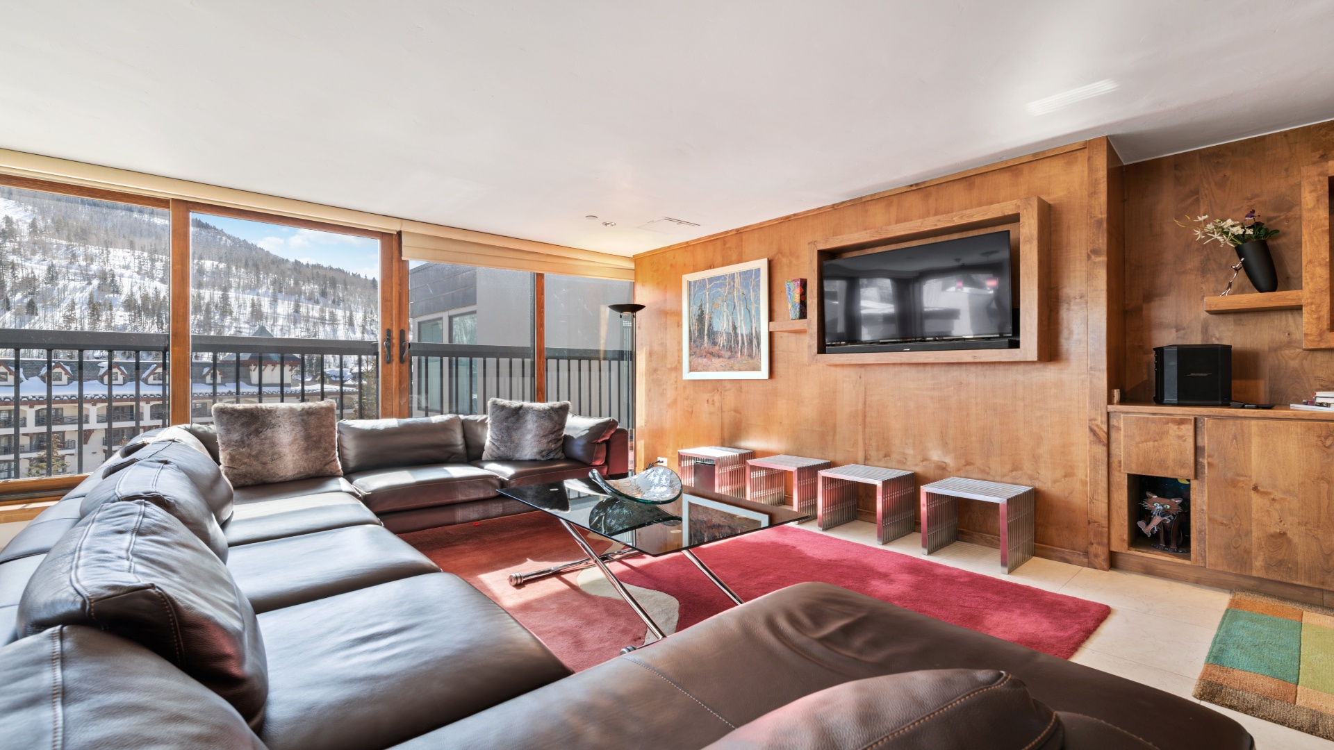 Sink into plush leather seating and lose yourself in mountain views framed by floor-to-ceiling windows. Your alpine retreat combines warm wood tones with modern entertainment—perfect for unwinding after adventure-filled days.