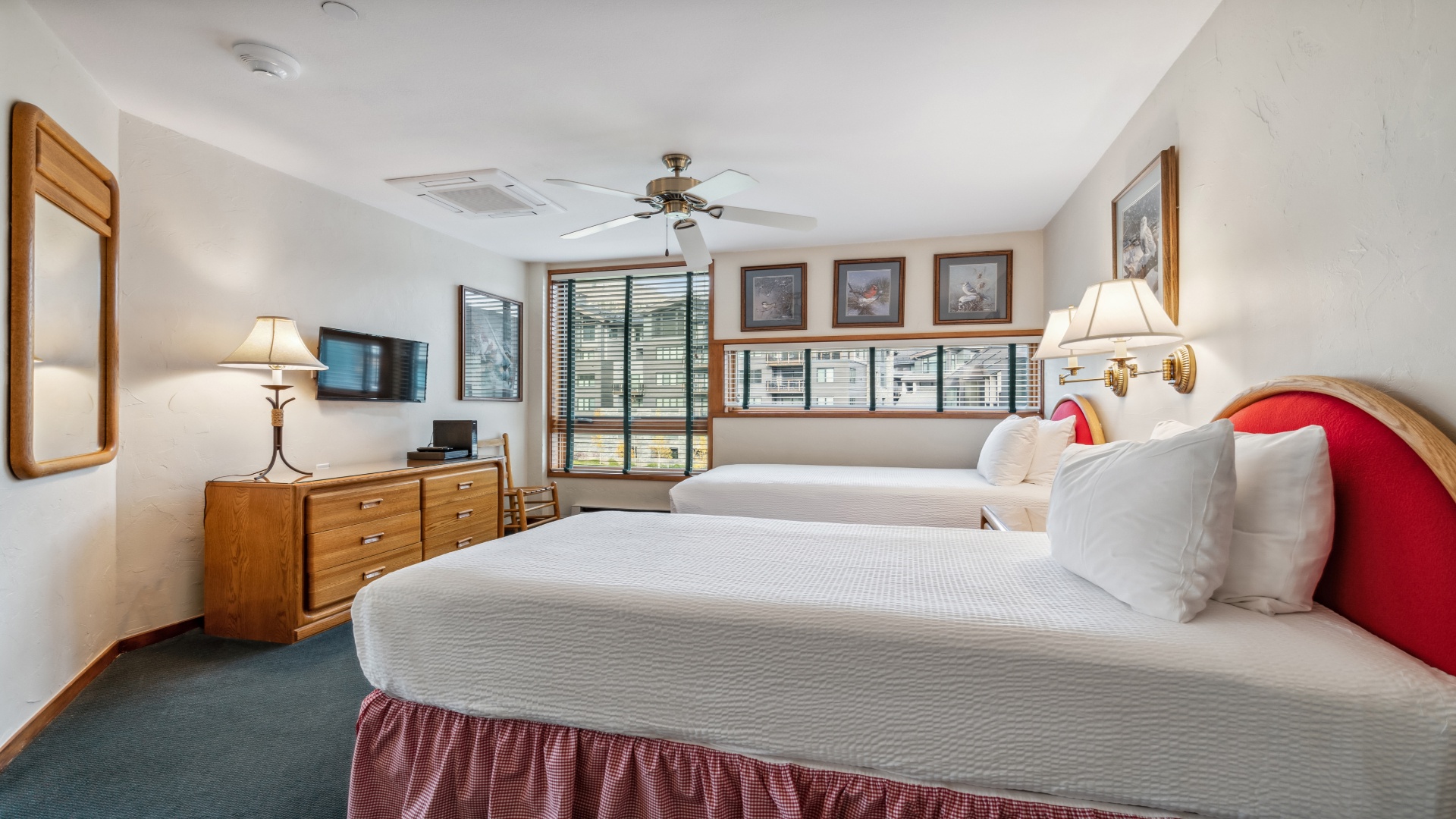 Rest easy in your cozy bedroom, where two plush beds invite peaceful sleep and warm wood details create an inviting mountain retreat. Ceiling fan and natural light enhance your comfort.