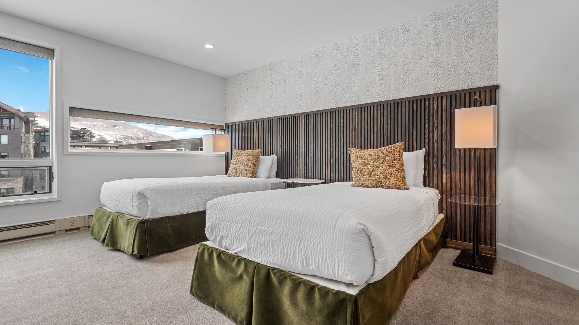 Relax in your serene twin bedroom with plush beds, modern décor, and a mountain view through the window—perfect for restful nights after mountain adventures.