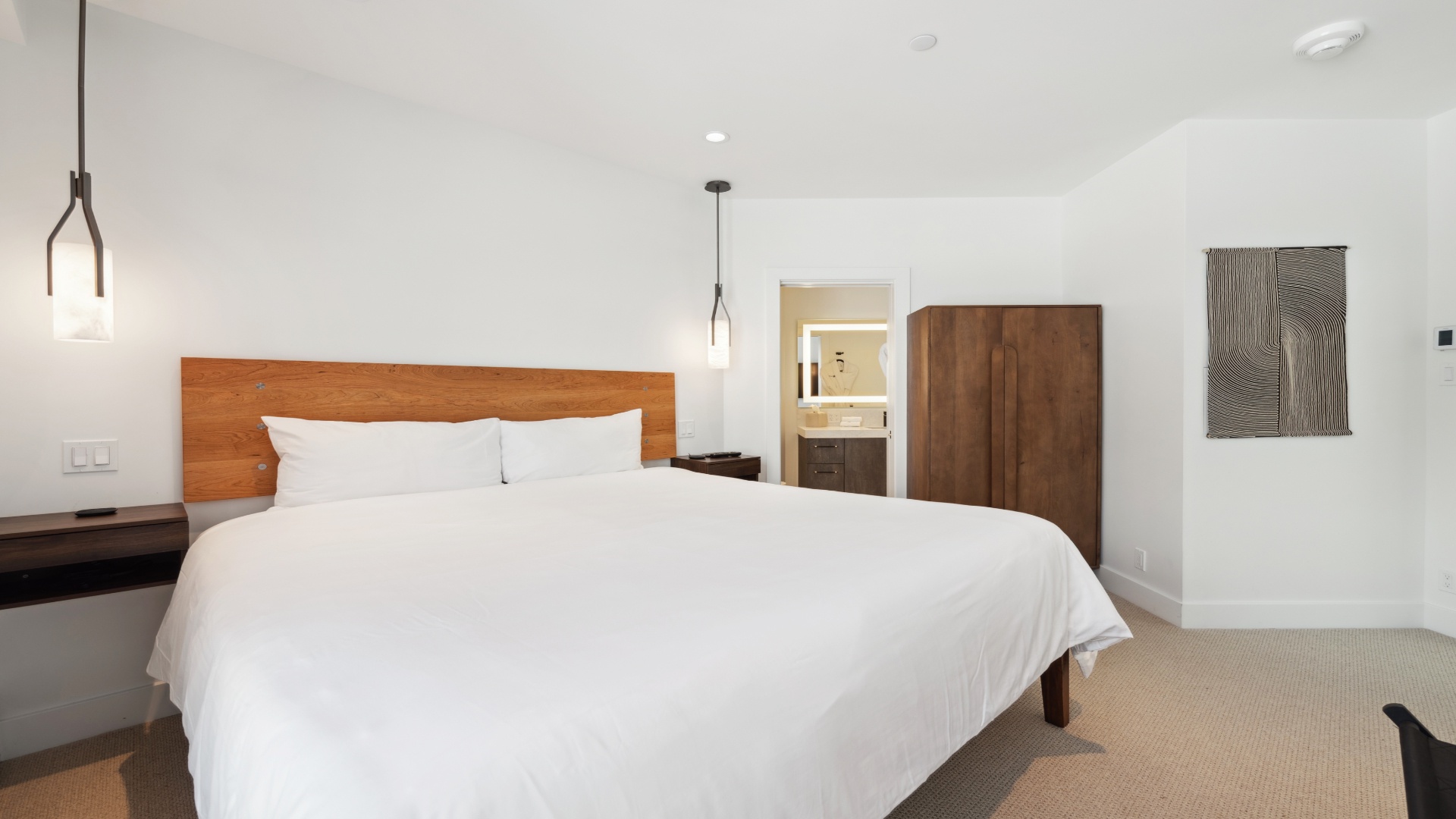 Picture yourself unwinding in this serene bedroom, where clean lines and warm wood tones create a peaceful retreat. Sink into the plush white linens and let the day's stress melt away in your private haven.