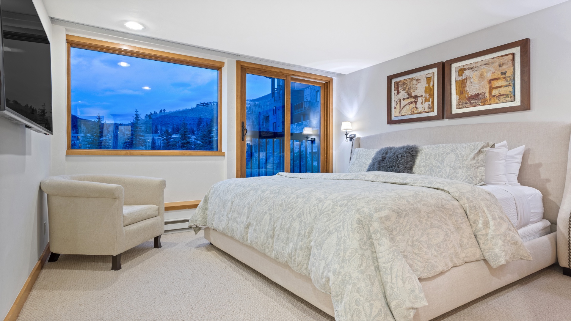 Sink into plush bedding and wake to stunning mountain views framed by alpine windows. Your peaceful retreat features cozy seating and art-filled walls creating the perfect escape after a day of adventure.