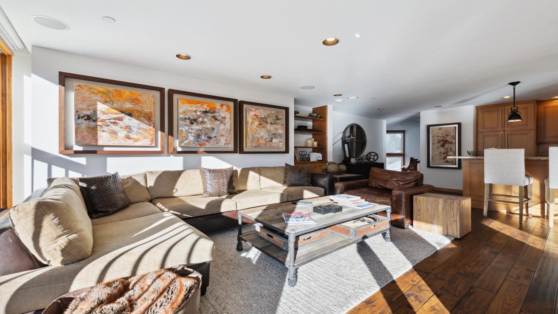 Sink into plush sofas and unwind in your sunlit living space. Warm wood floors and curated artwork create an inviting atmosphere perfect for relaxation or conversation.