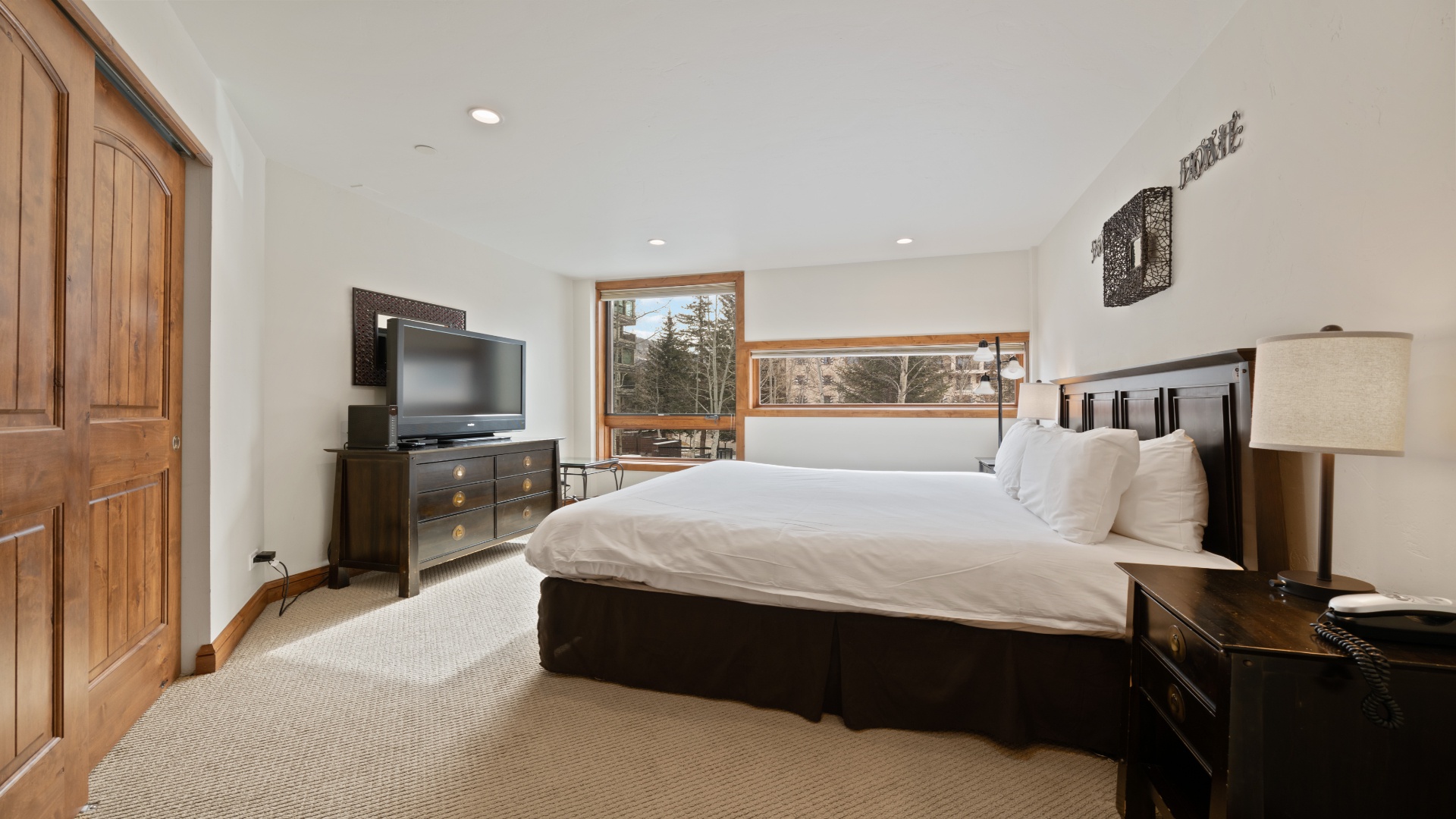 Wake up to mountain views through expansive windows in your serene bedroom, where plush bedding and natural light create the perfect retreat after a day of adventure.