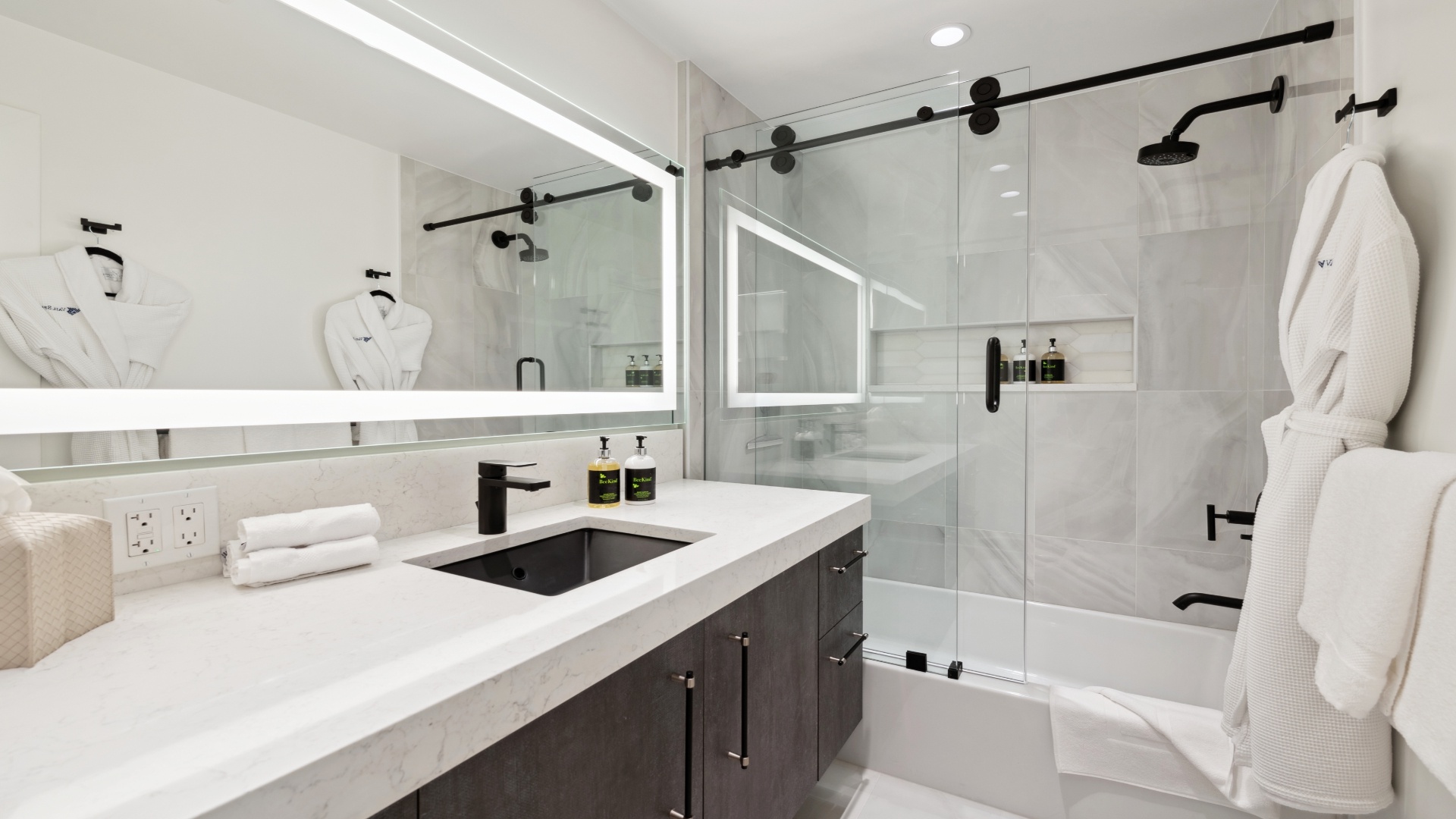 Step into a modern, spa-like bathroom with sleek fixtures, plush robes, and a spacious glass-enclosed shower—your own serene retreat for ultimate relaxation.