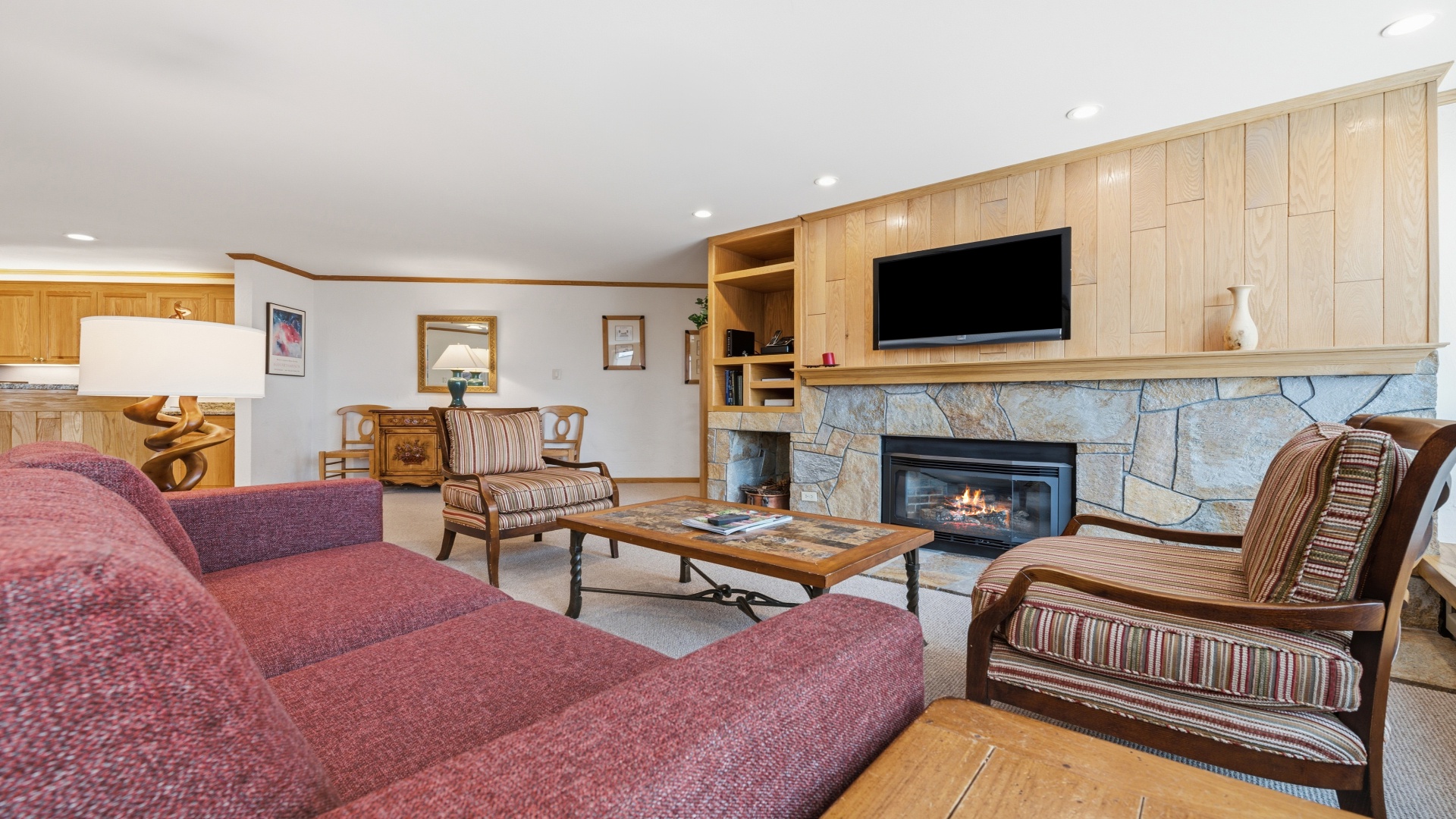 Unwind in your spacious living room with warm wood accents, a cozy stone fireplace, and plush seating where you can relax after a day of adventure.