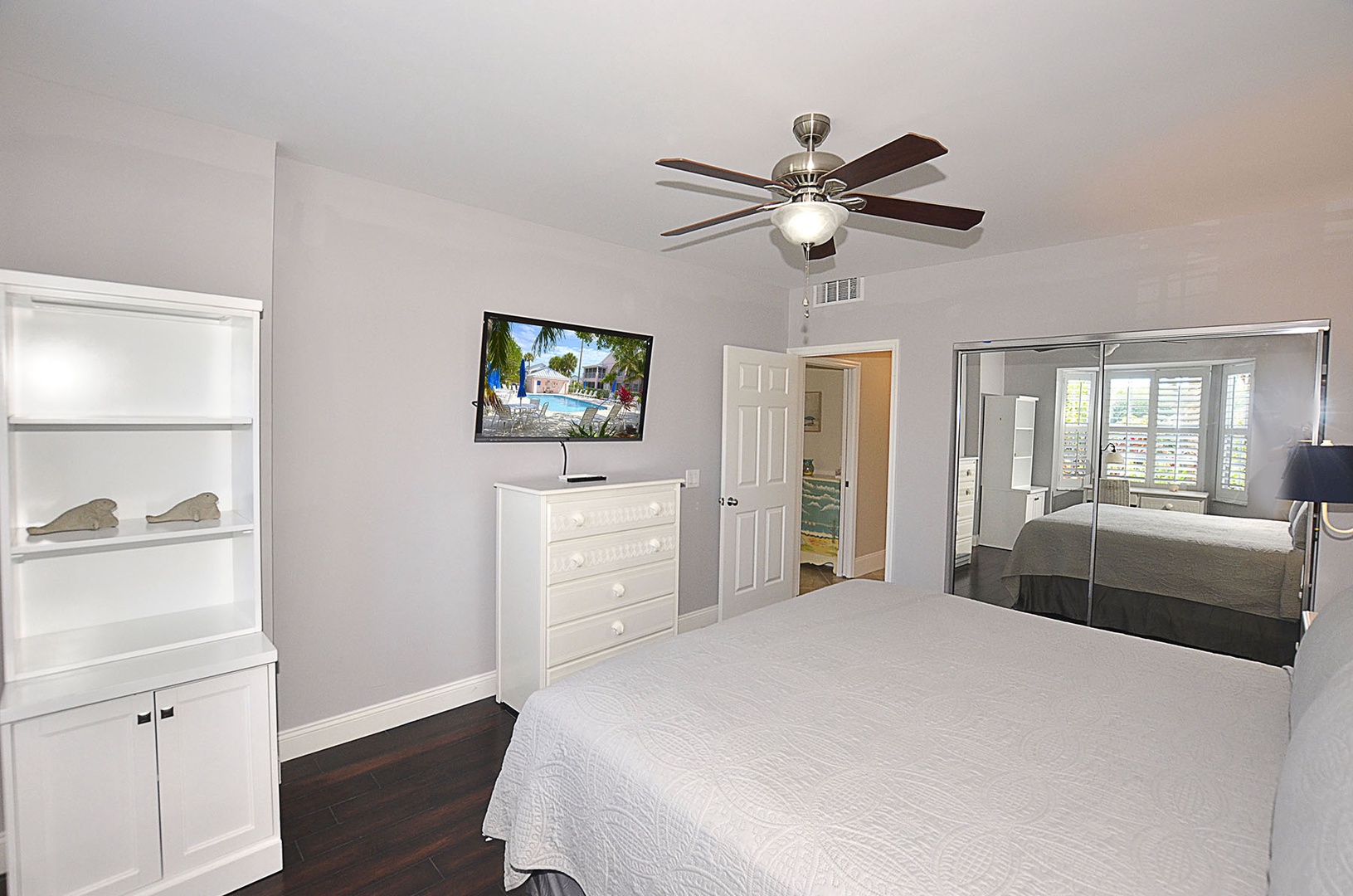 Guest bedroom with flat-screen TV, and mirrored closets.