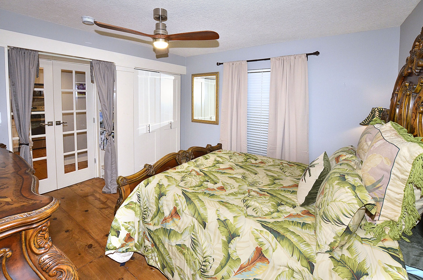 Guest Bedroom. Relax in your tropical-themed bedroom with elegant wooden furnishings, cooling ceiling fan, and natural light streaming through your windows.