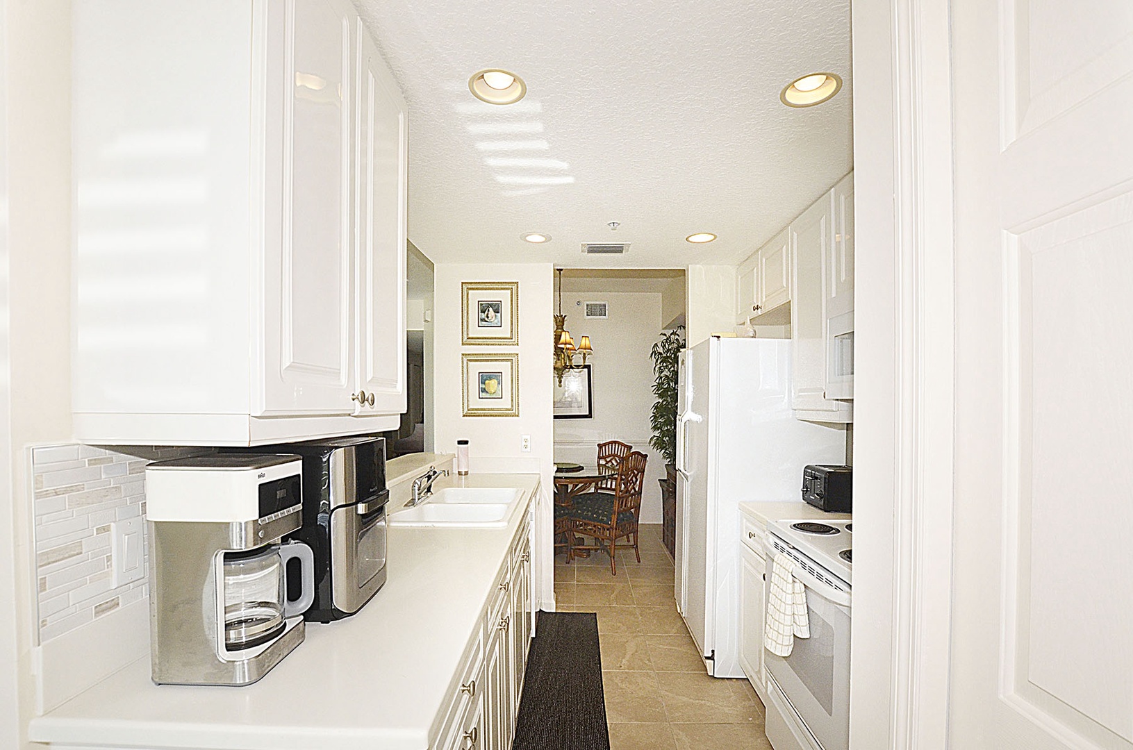 Enjoy the fully equipped galley kitchen, featuring modern appliances and bright white cabinetry.