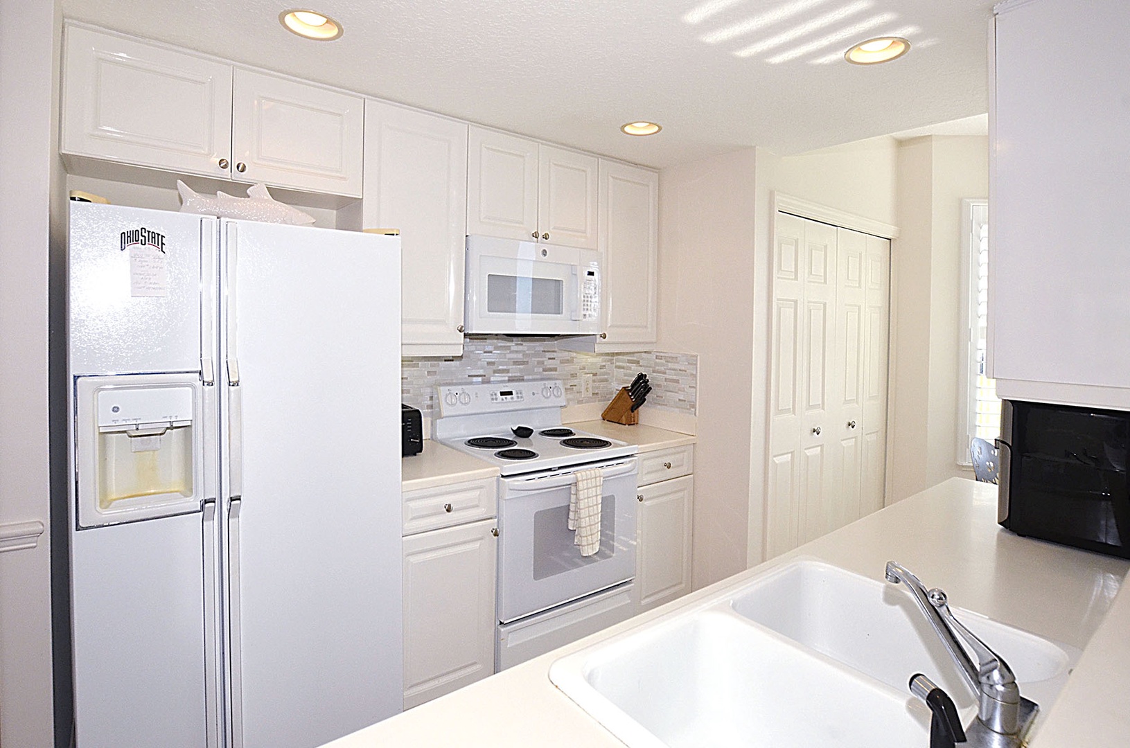 Your bright, fully-equipped kitchen awaits with white appliances and ample counter space for preparing meals during your stay.