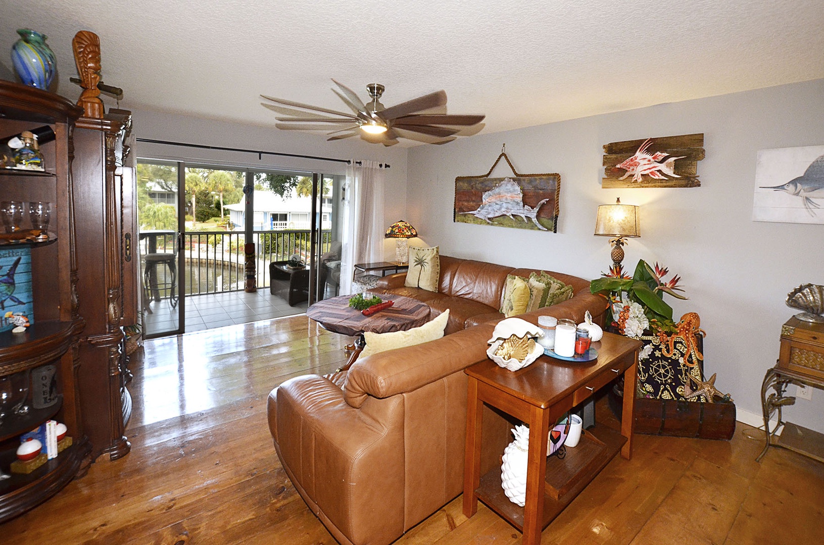 Living Room. Relax in your tropical-themed living room with leather seating, ceiling fan, and balcony views of lush surroundings.